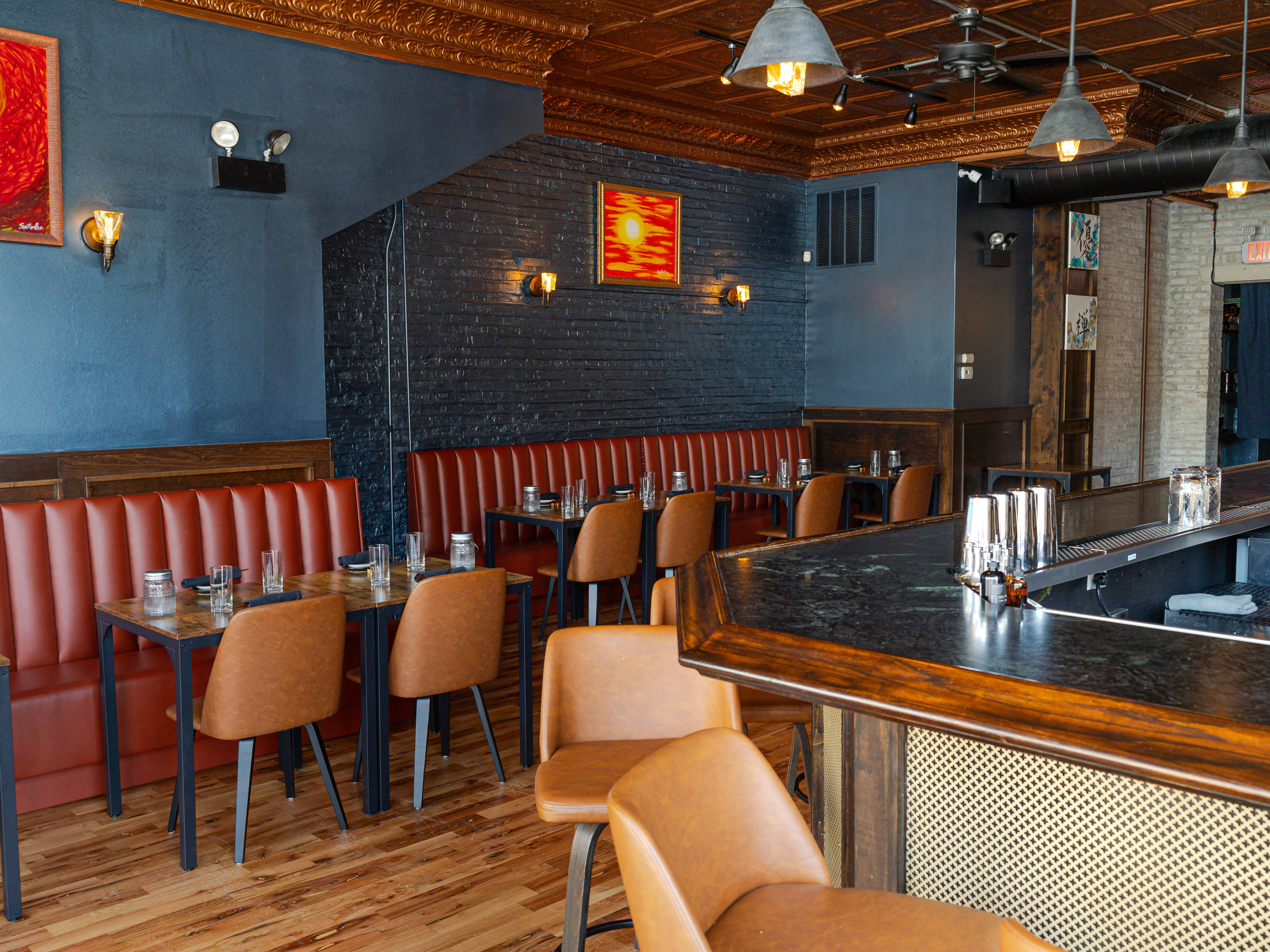 A dining room with booths, leather chairs, wooden tables, and a bar.