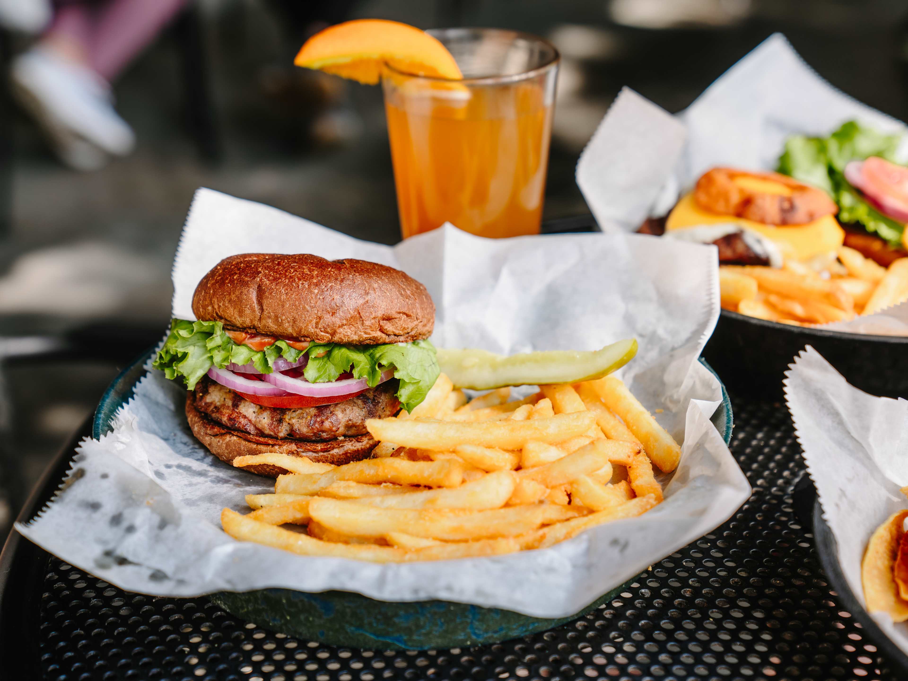 A basket of fries and a burger with lettuce, onions, and tomatoes.