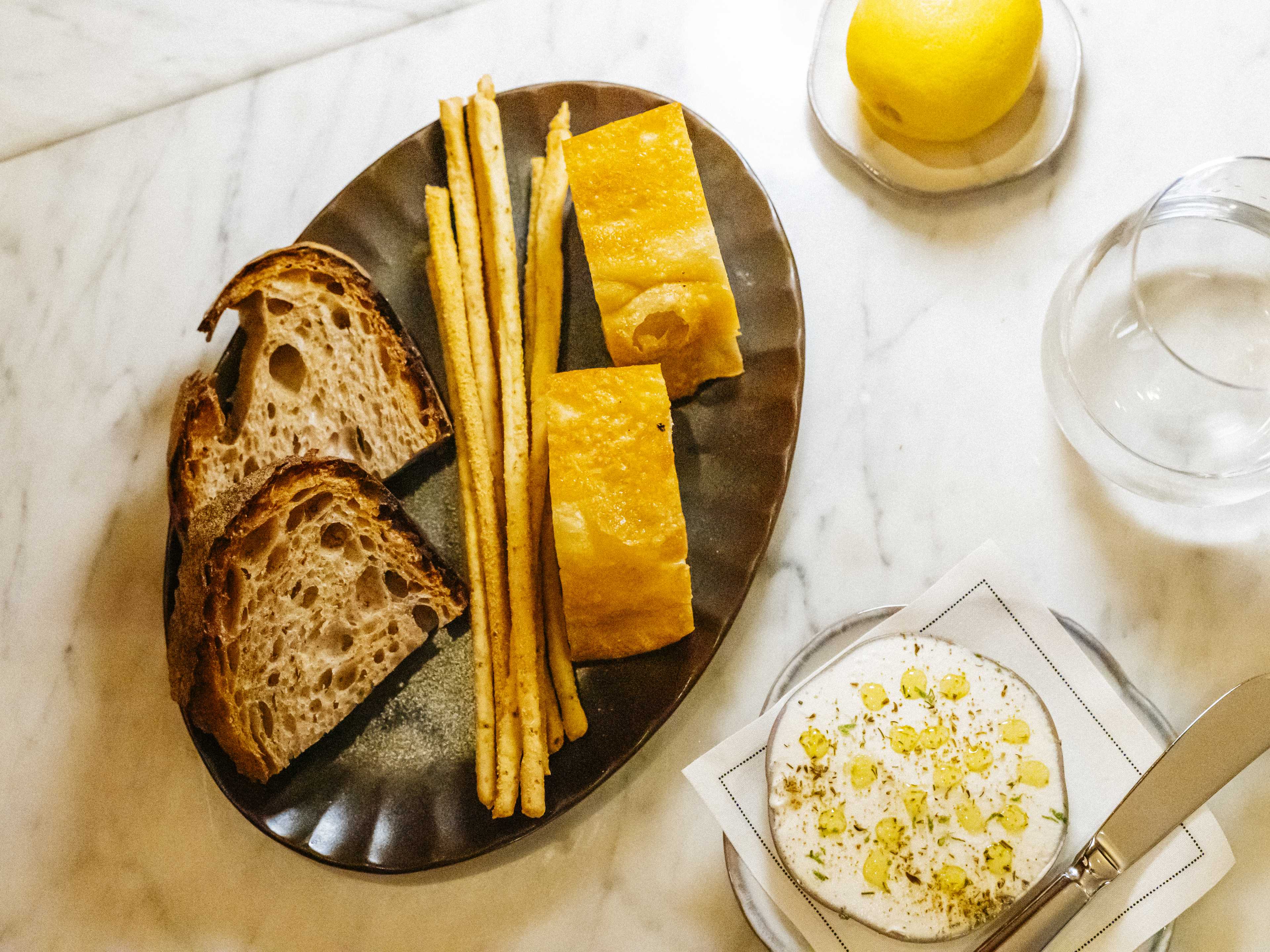 Plate of breadsticks and sliced sourdough at Giano