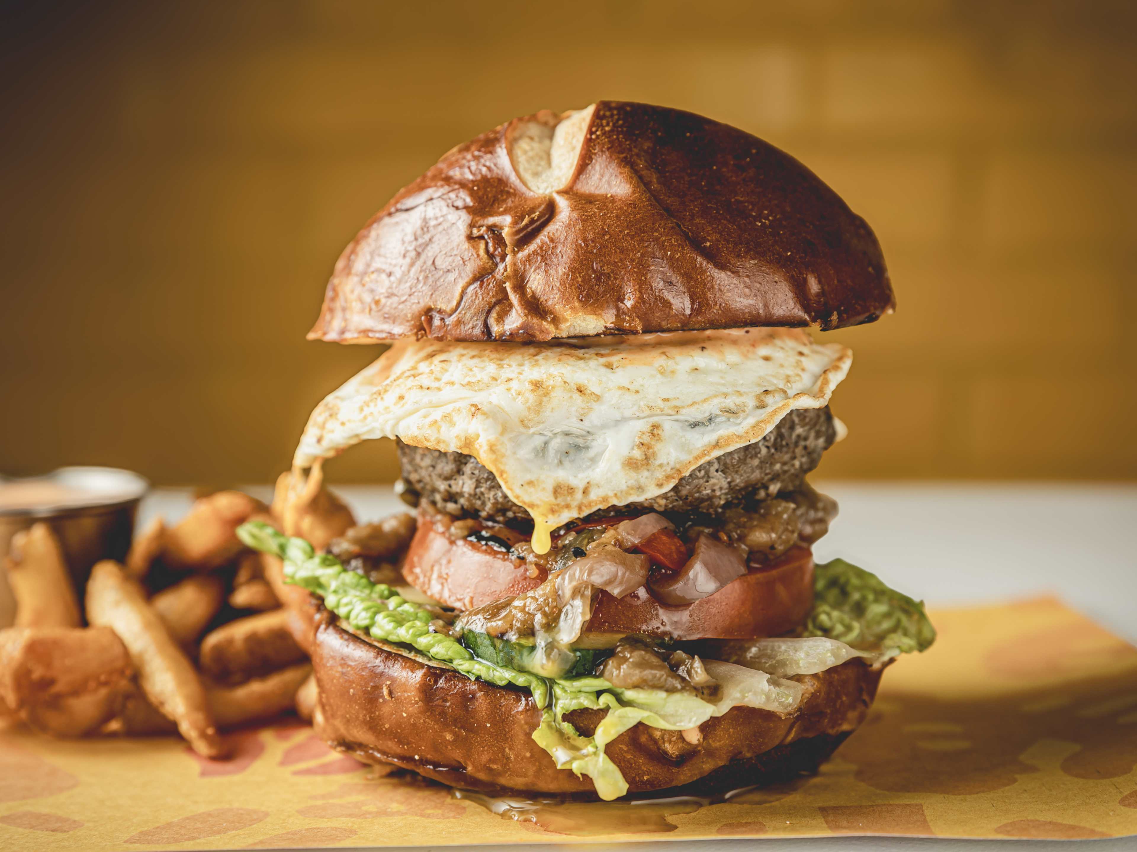 burger with a fried egg and green curry sauce on yellow butcher paper