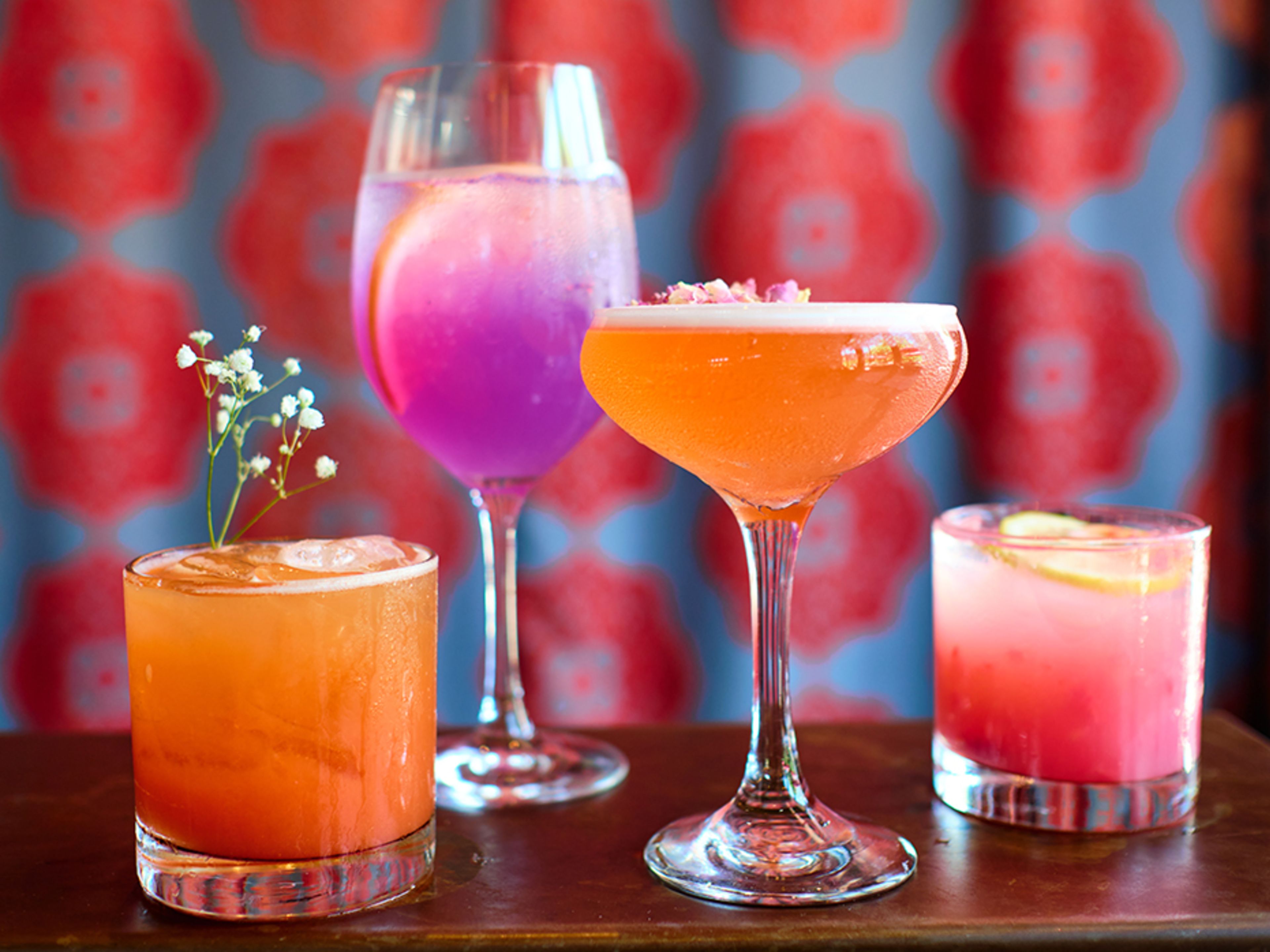 Four purple, pink, and orange cocktails.