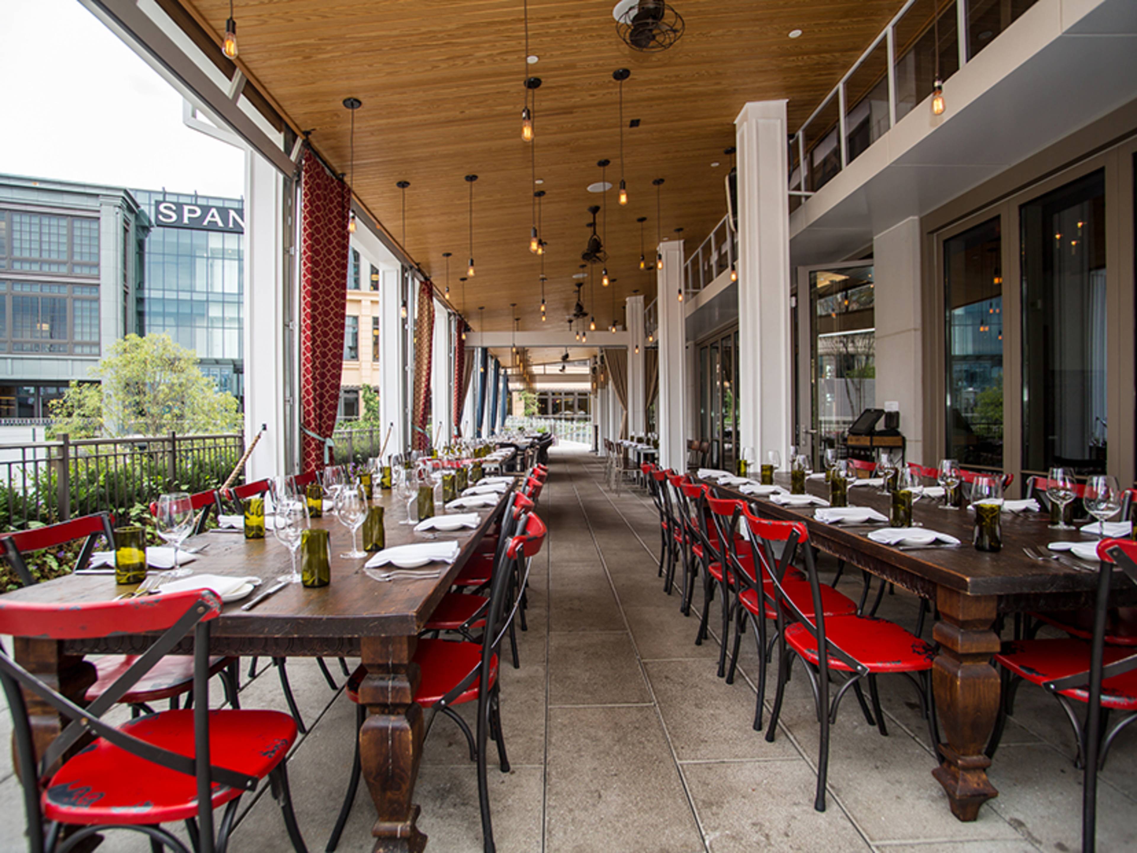 The patio of Gypsy Kitchen with red chairs and long wooden tables.