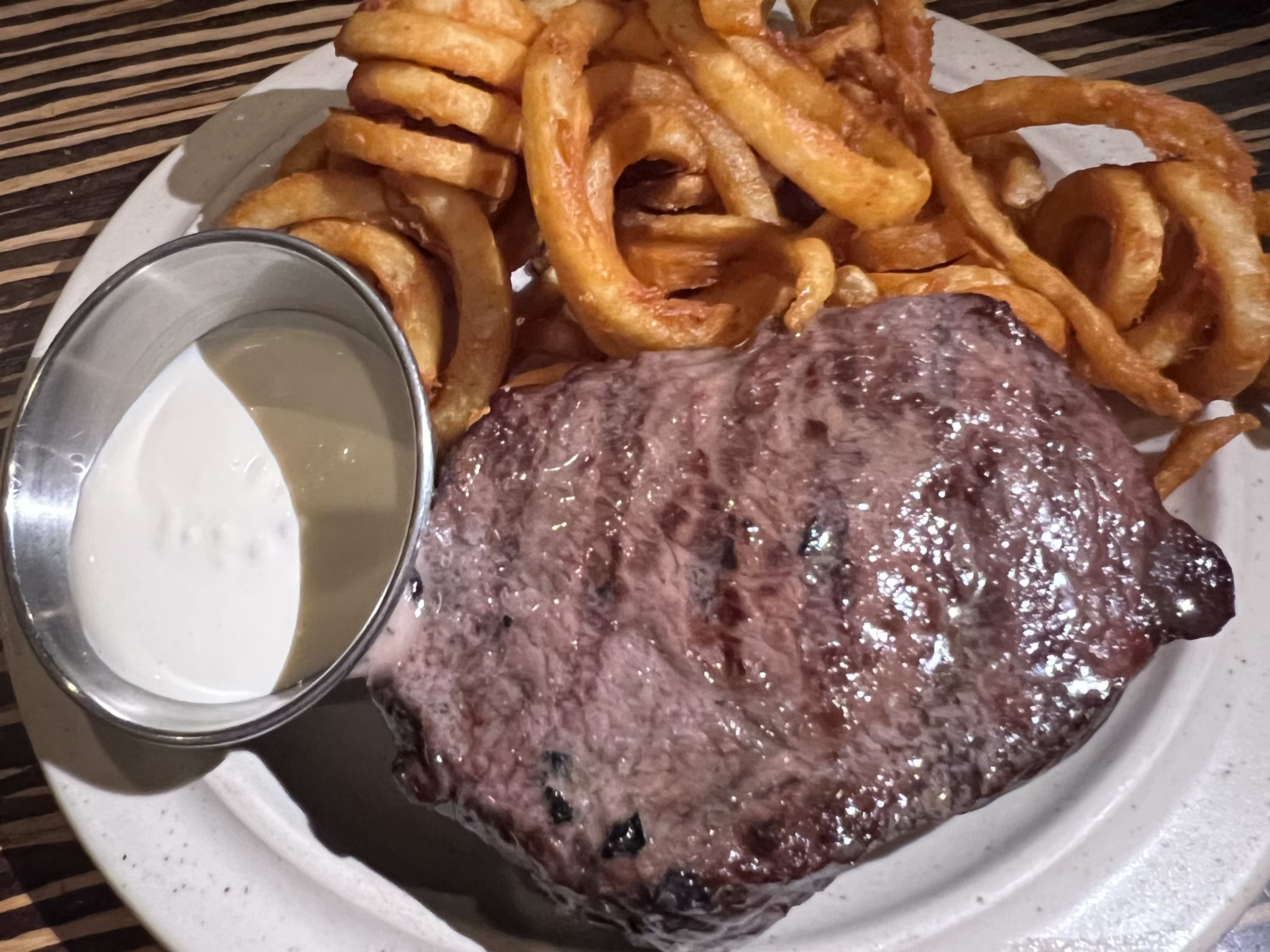 Steak on a plate with fries and sauce