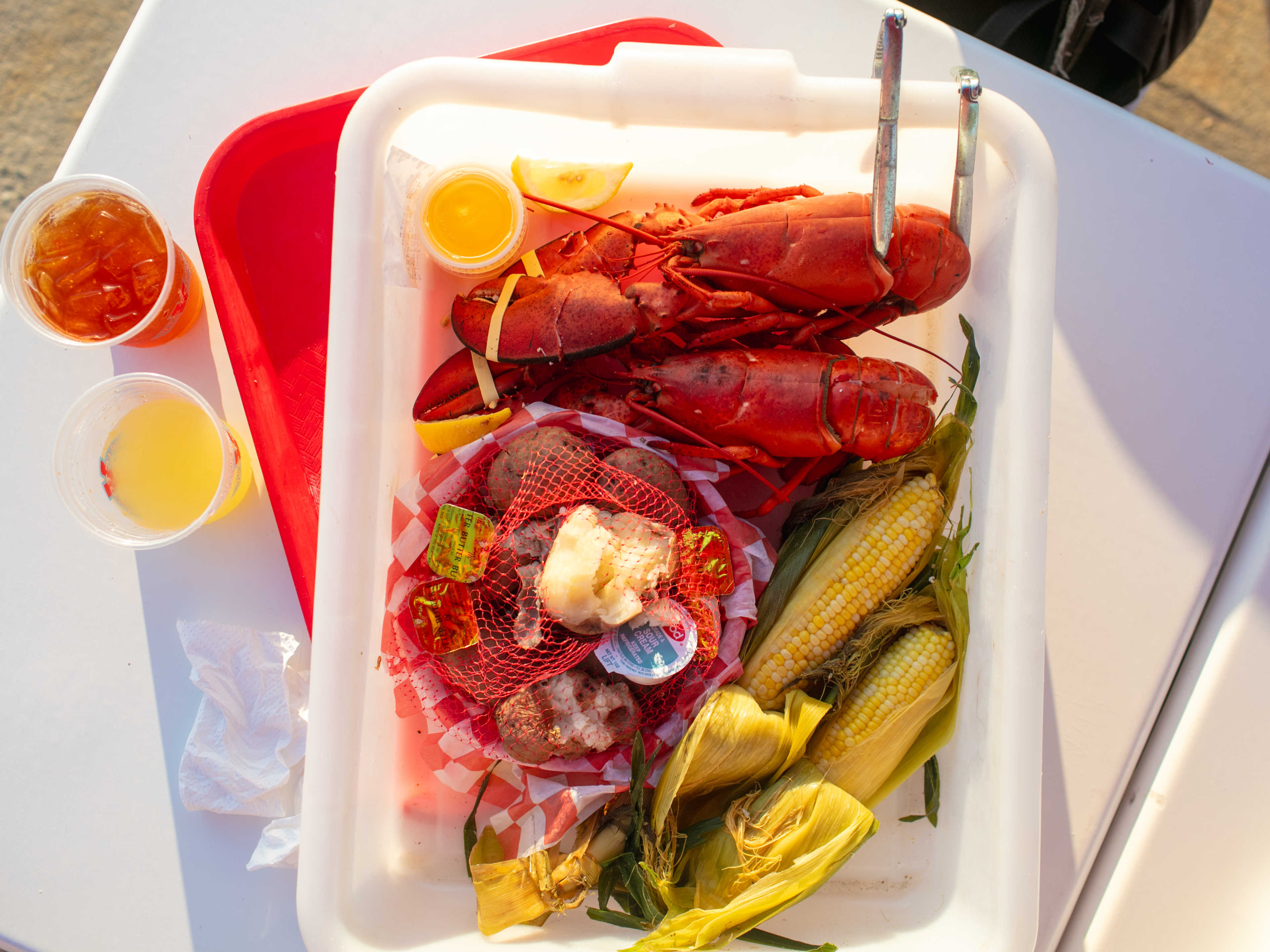 An overhead shot of lobsters and corn on a tray