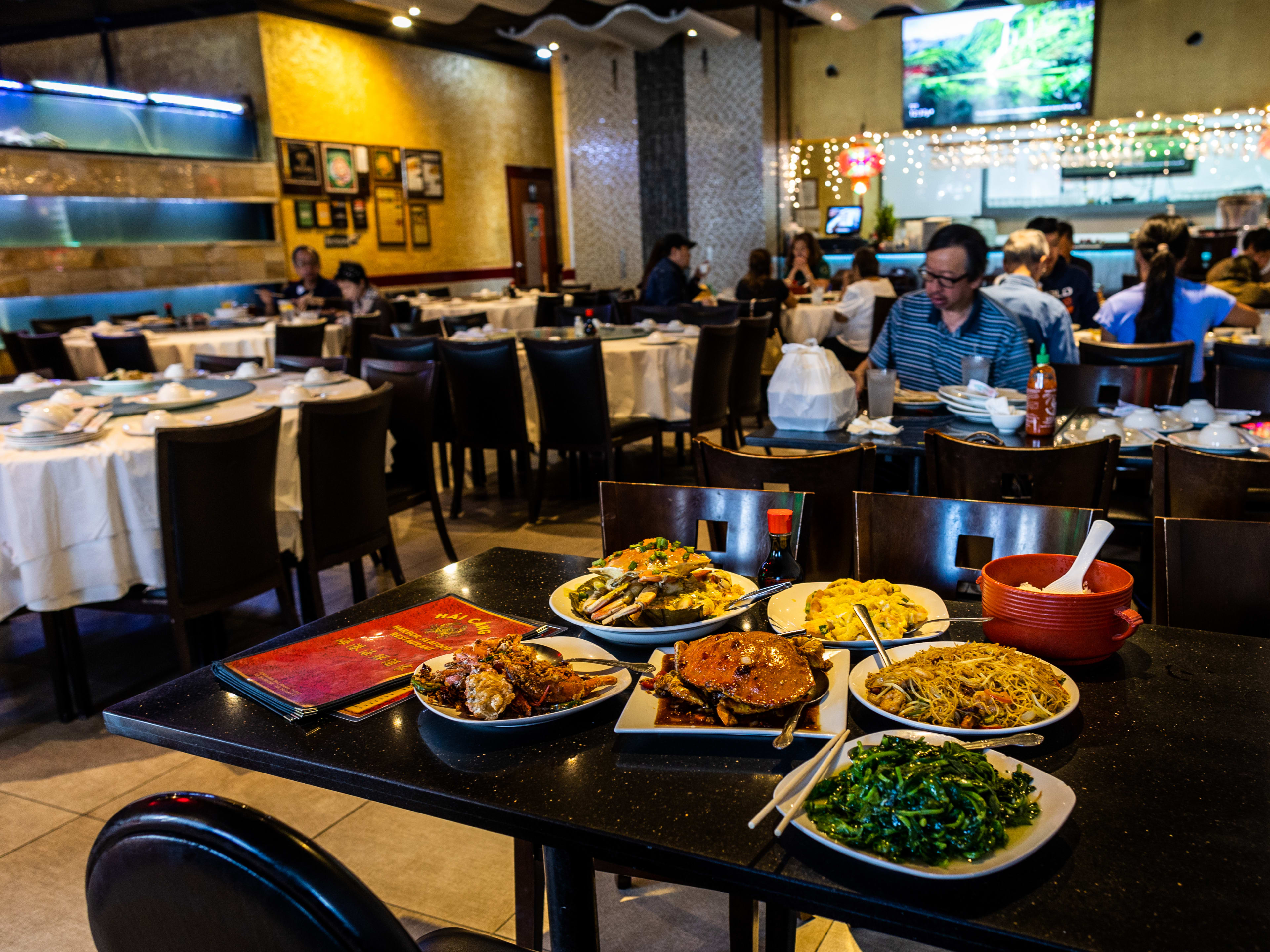 A variety of dishes served on white plates on a black table inside the dining area at Hai Cang.