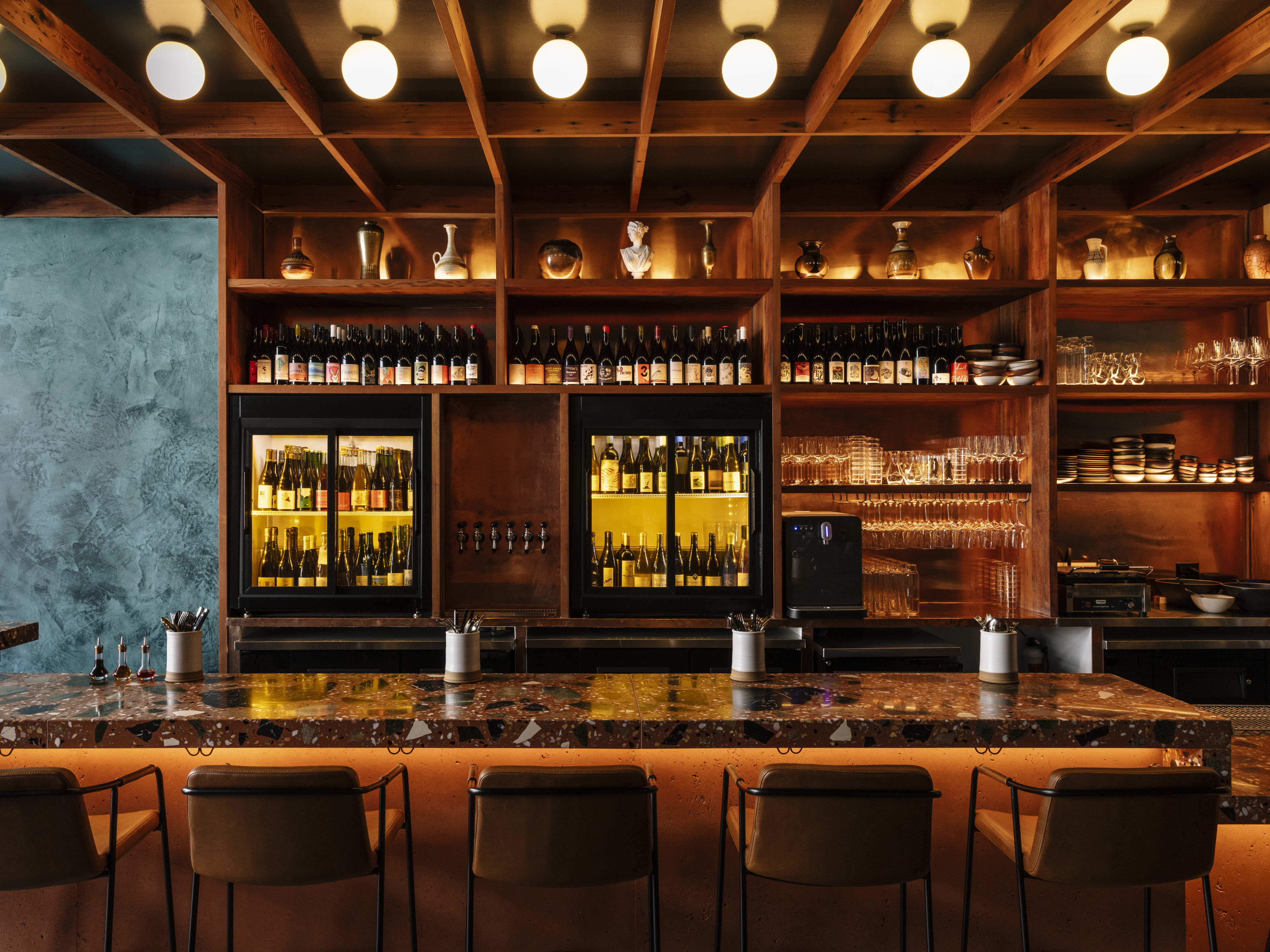 Wood paneled bar with wine fridges and glassware on display