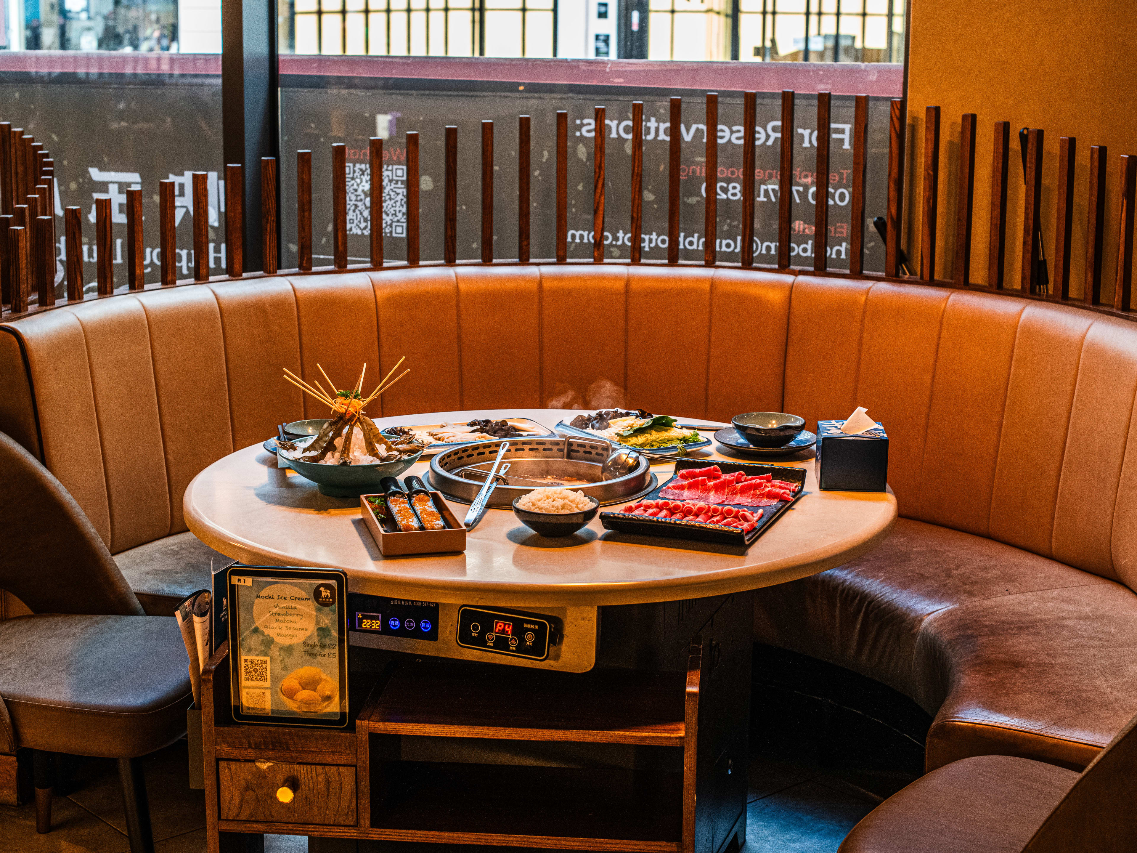 A large half moon shaped booth with food on the table at Happy Lamb Hotpot.