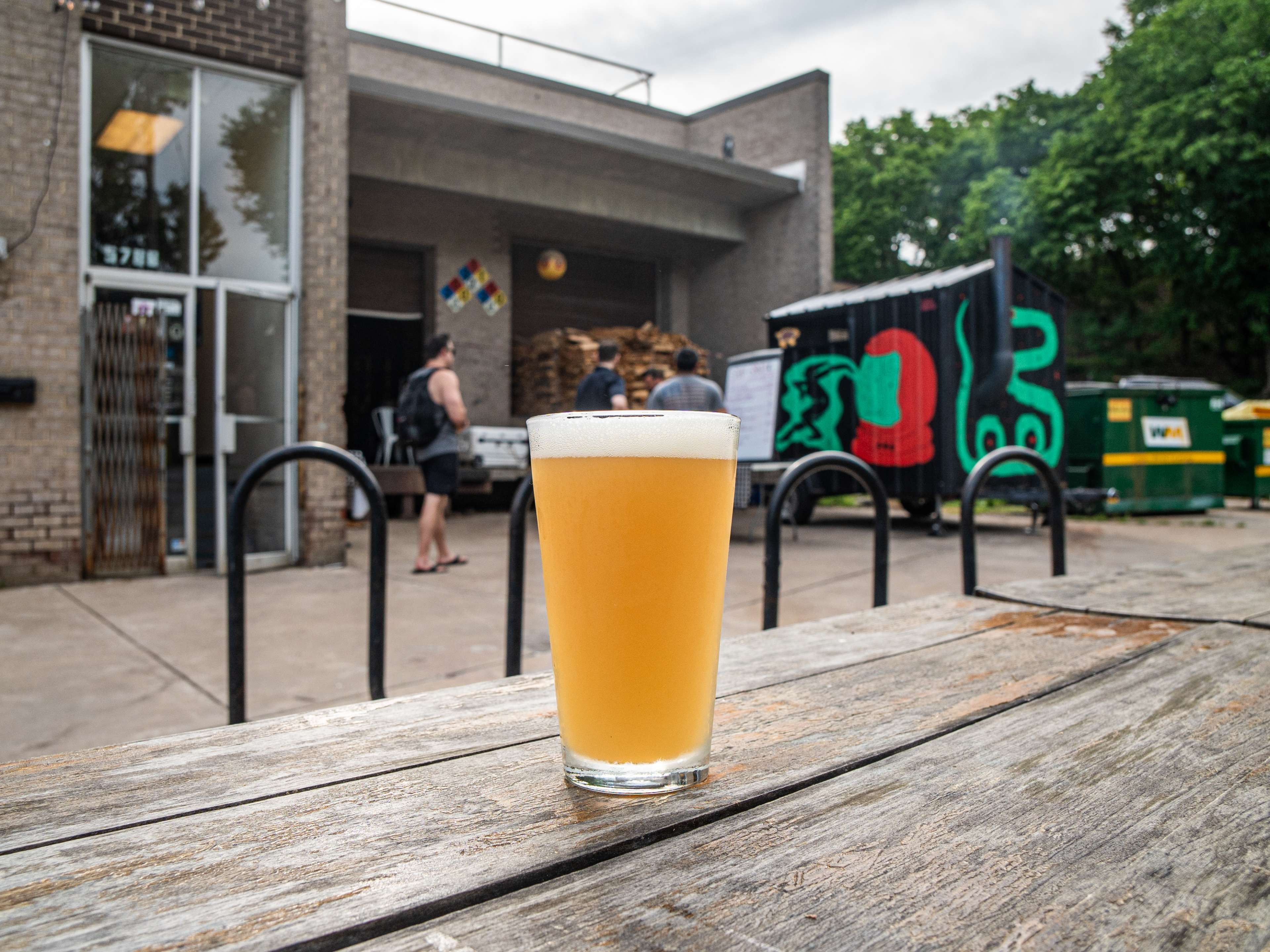 glass of beer on picnic table looking out onto brewery and food truck