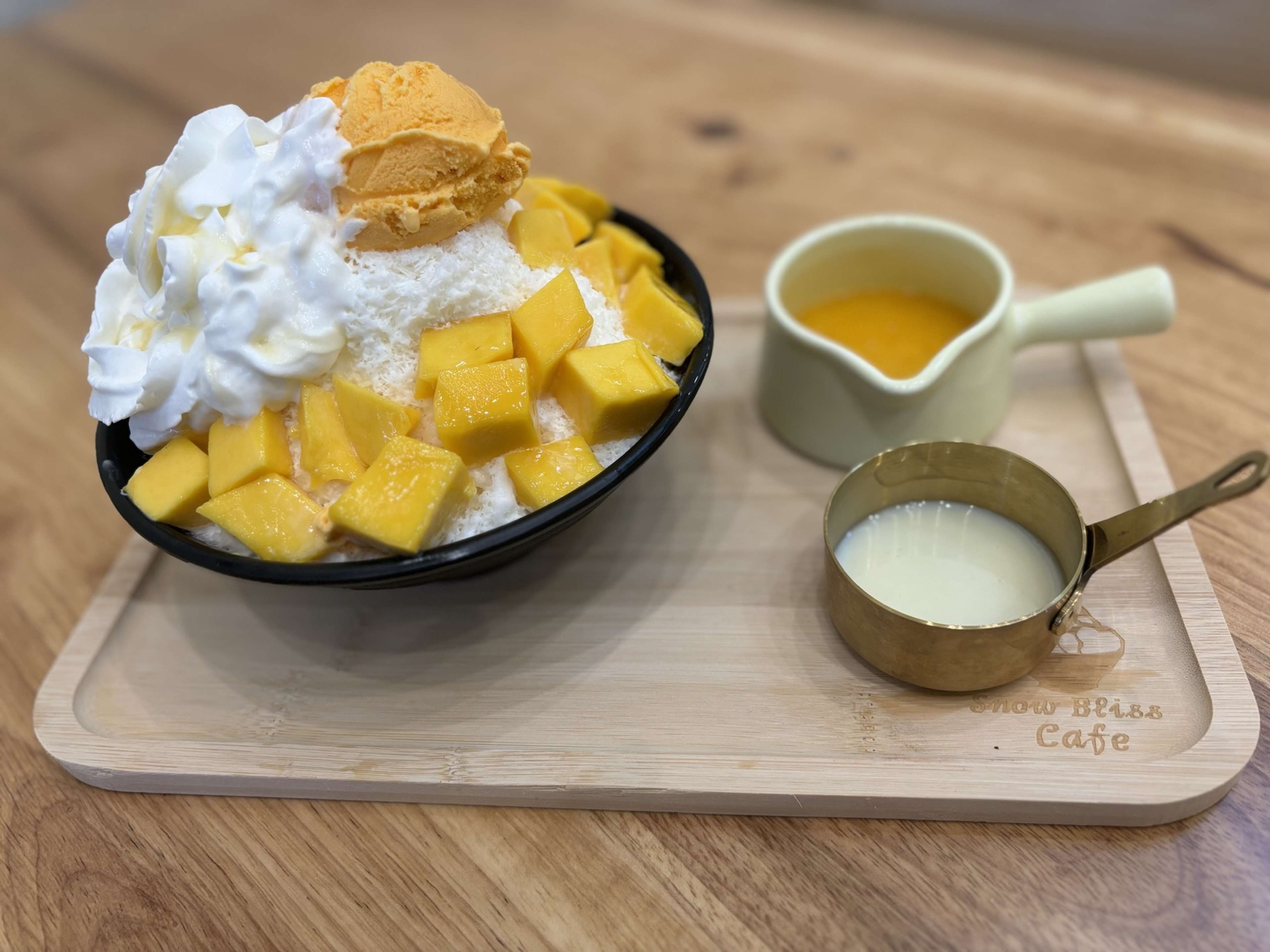 bowl of bingsu topped with mango chunks and whipped cream