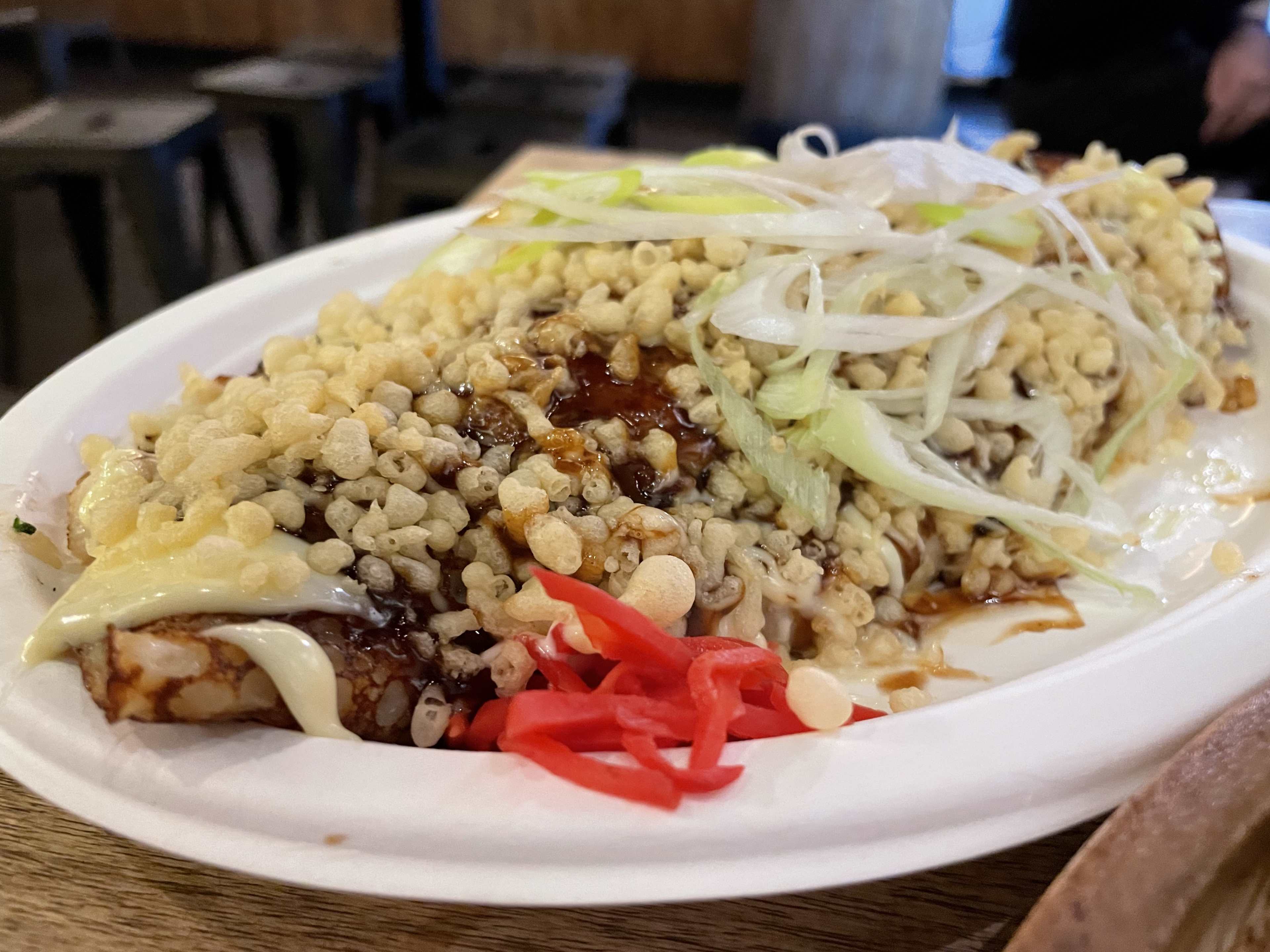 an okonomiyaki with crunchy tempura bites, scallions, and pickled ginger