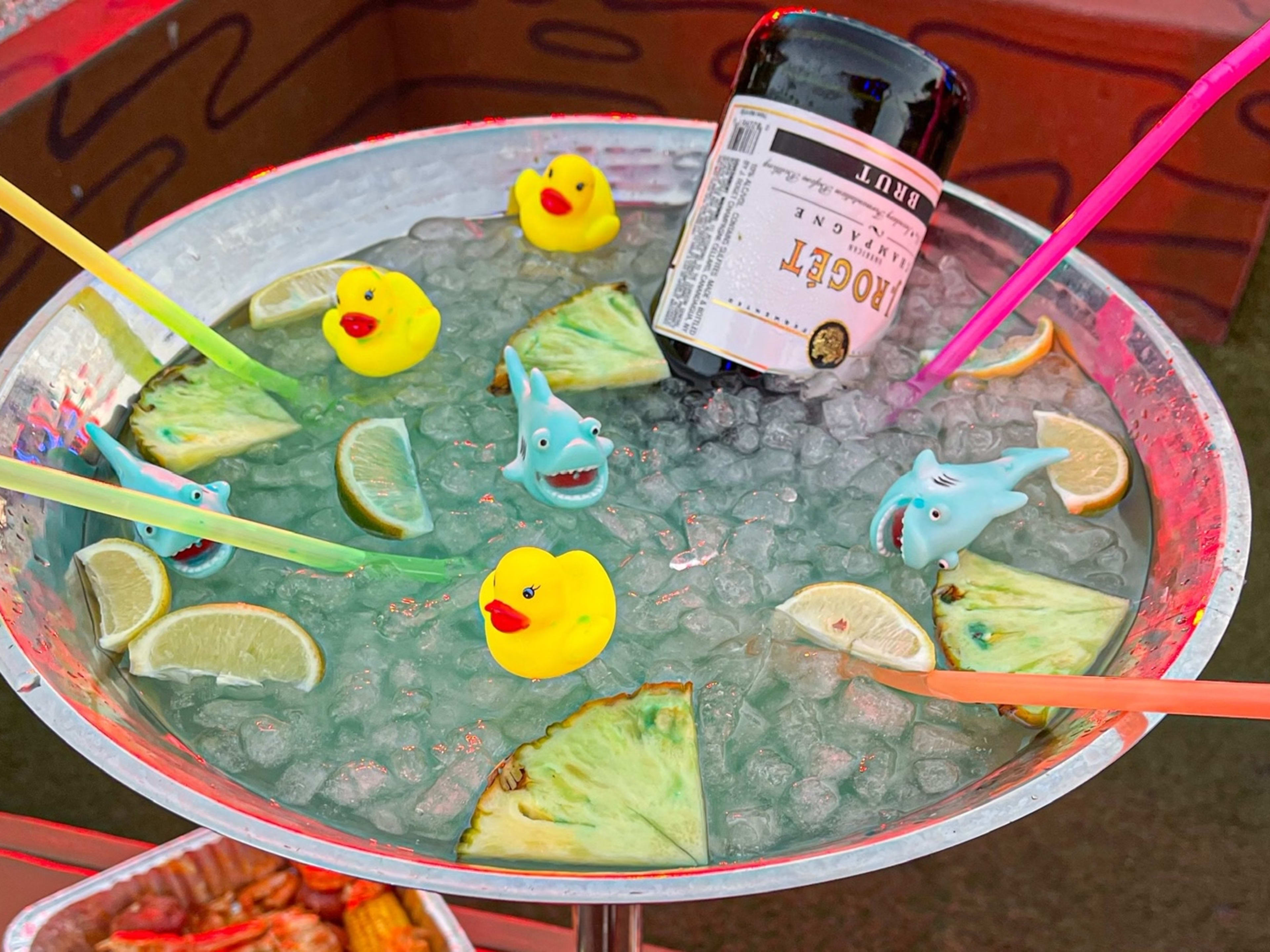 A large blue fishbowl cocktail with rubber ducks and fish floating on top.