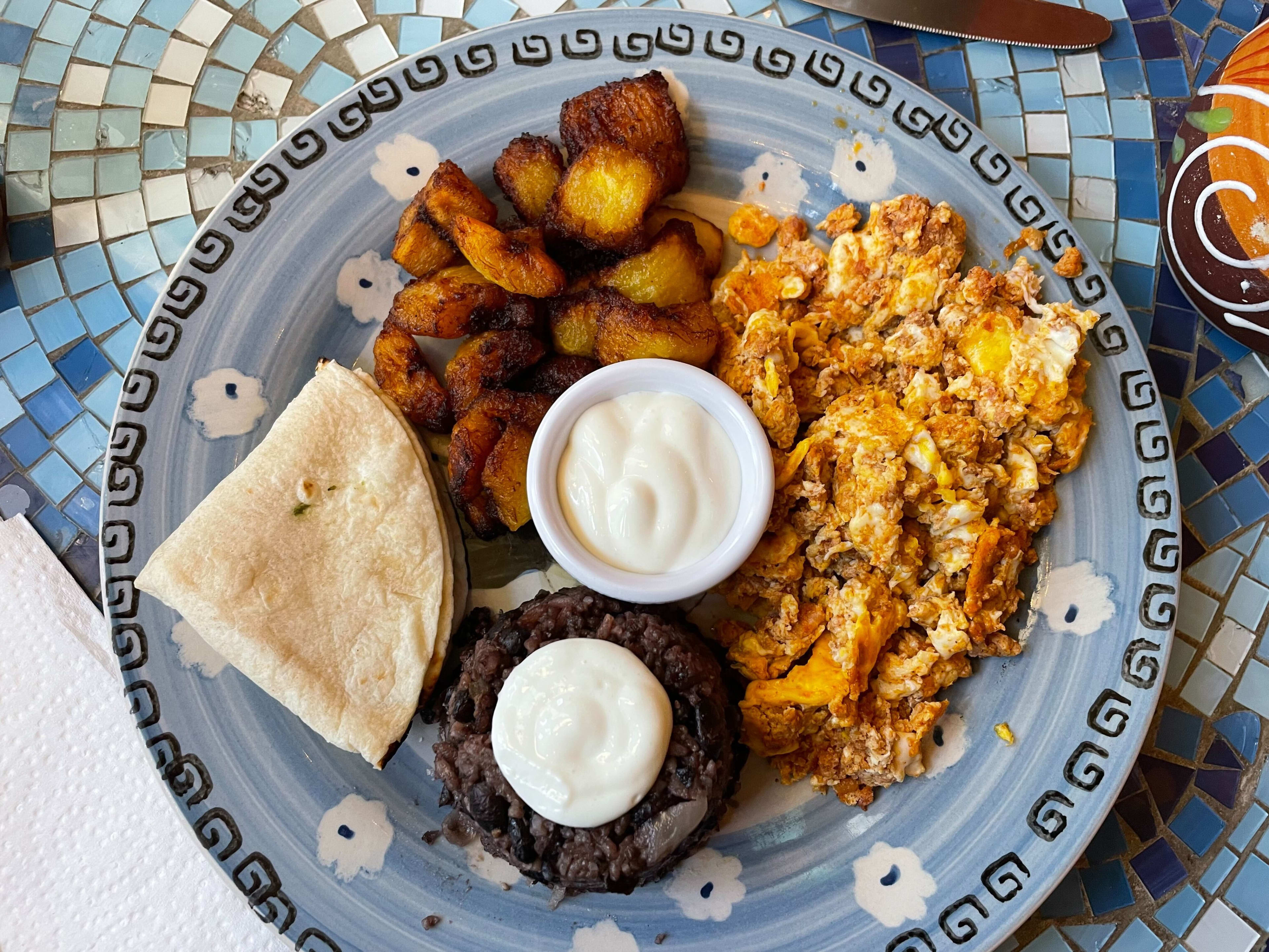 The plato tipico with fried plantains, a chorizo scramble, beans, rice, and tortillas