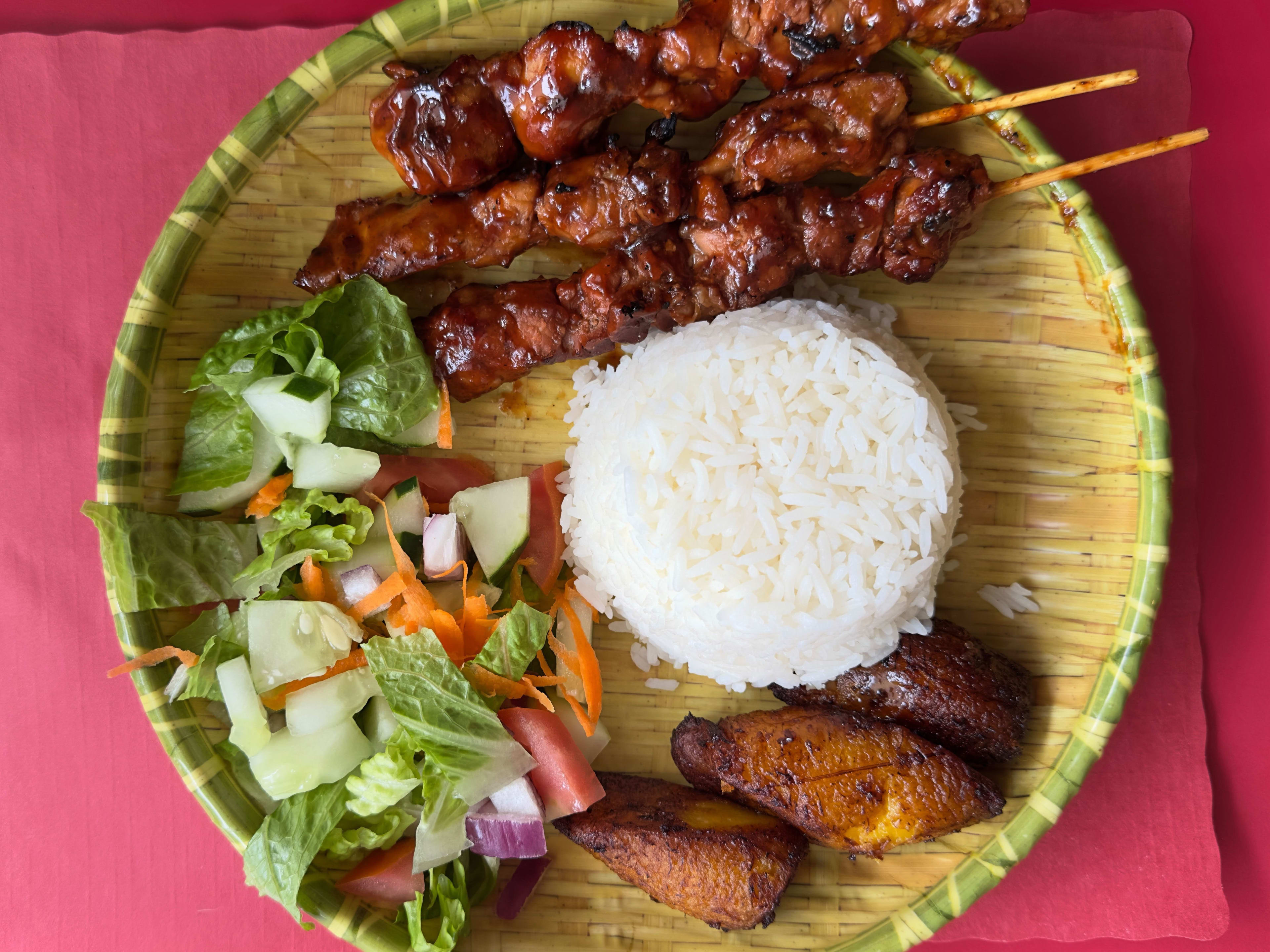 A plate with rice and a few barbecue meat skewers.