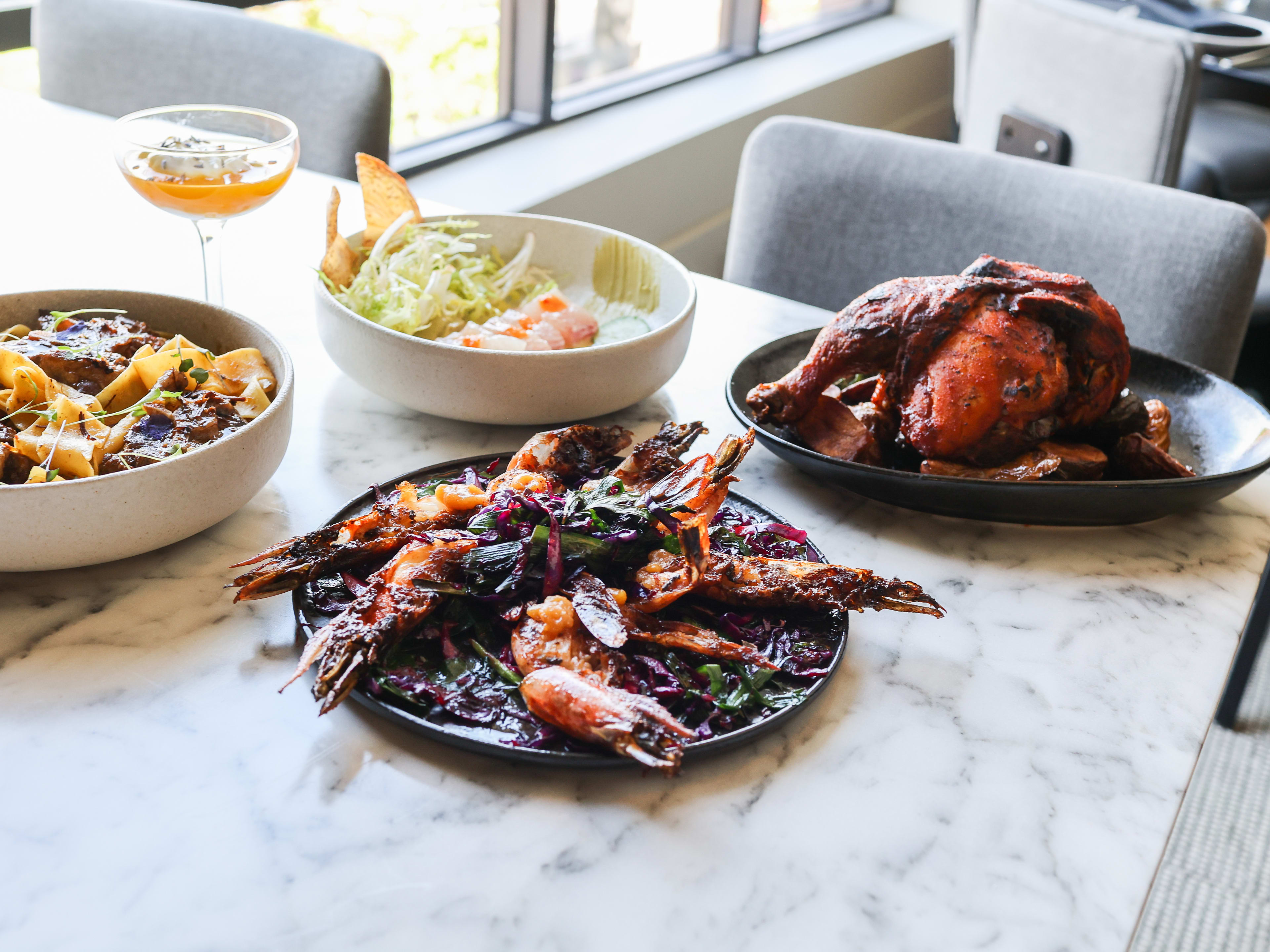 spread of dishes such as prawns, chicken, crudo, and pasta