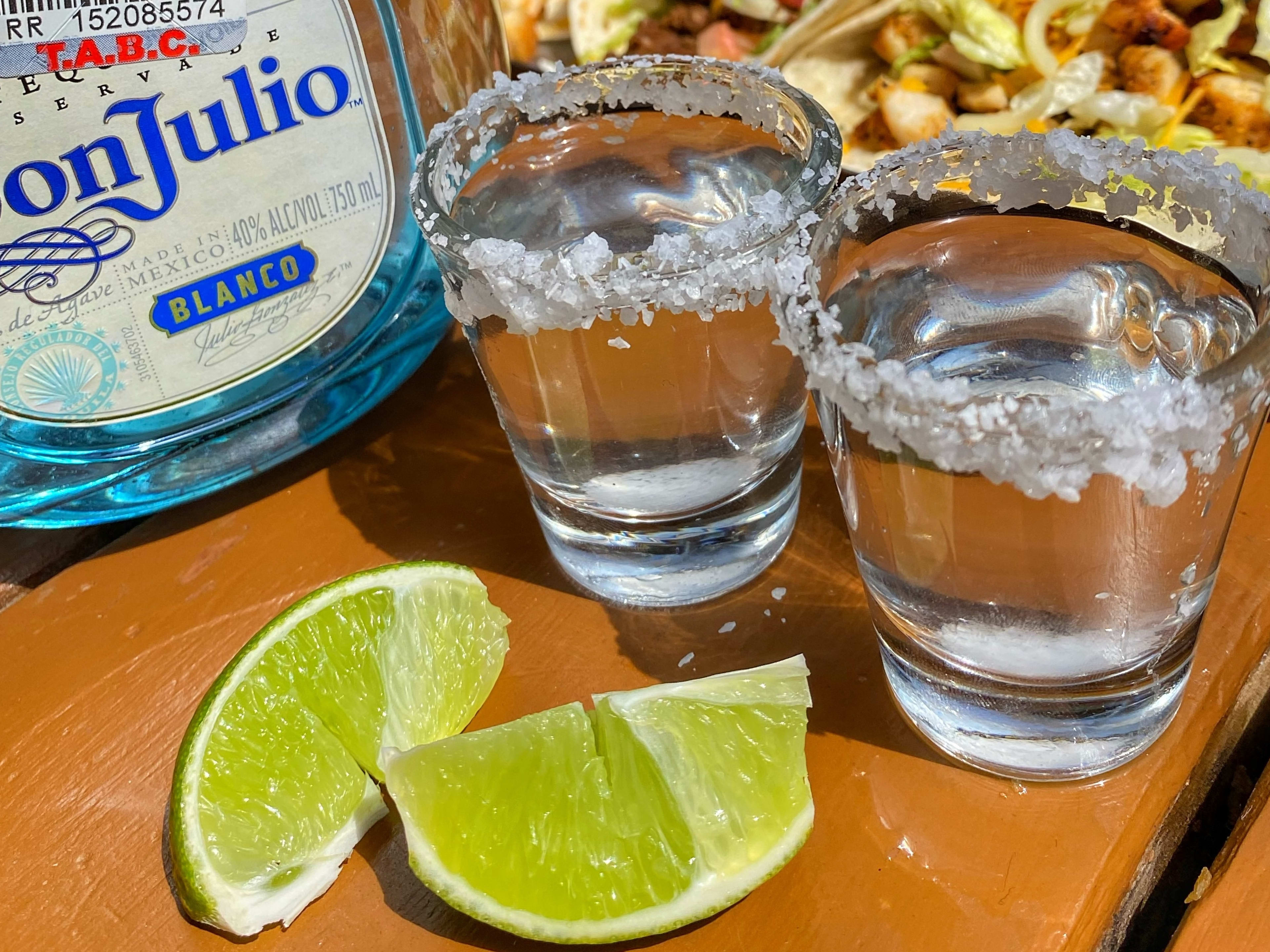 Two shots of Don Julio next to the bottle with two lime wedges.