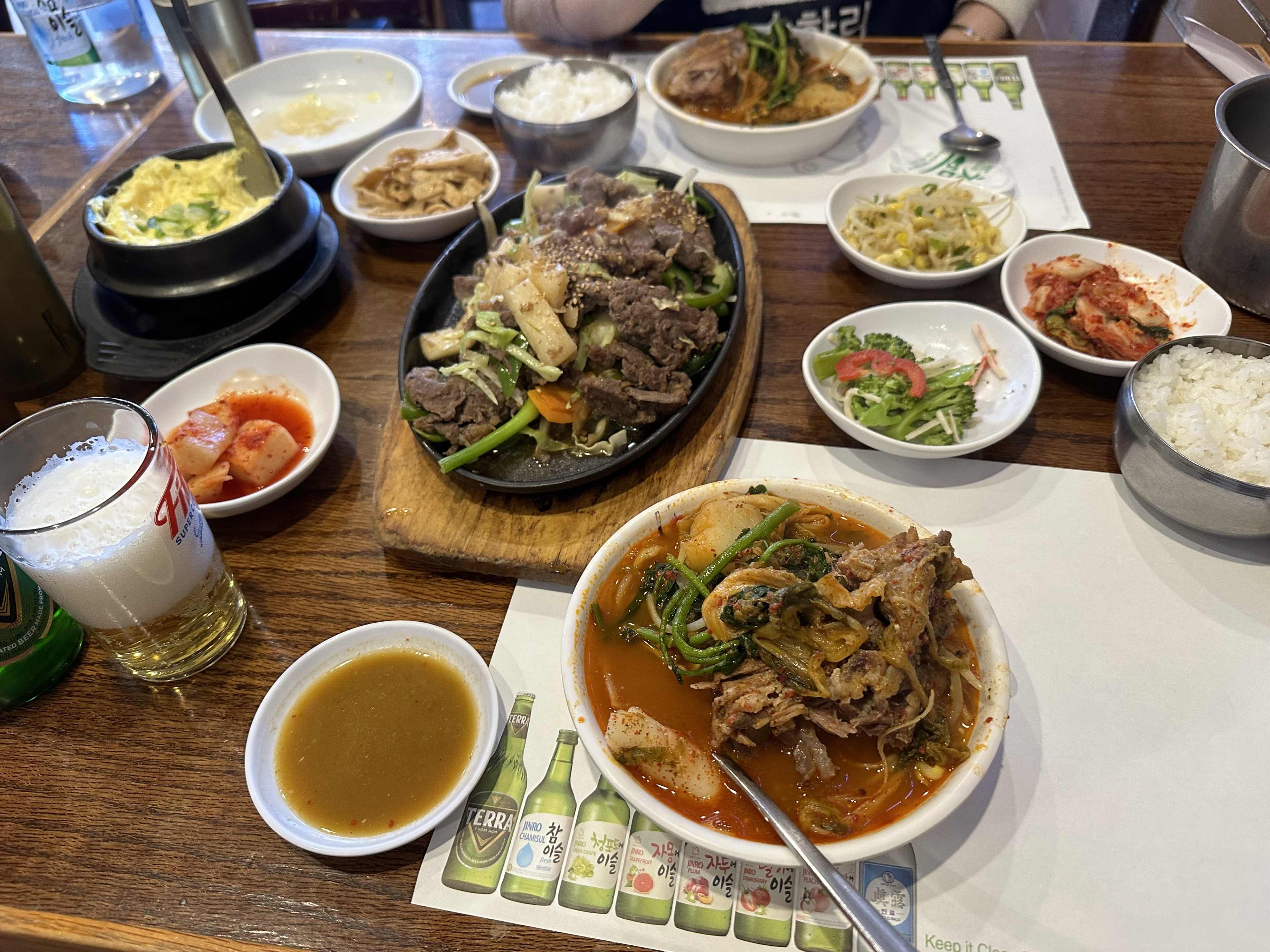 A big spread of Korean food, including soup, bulgogi, and banchan, on a table.