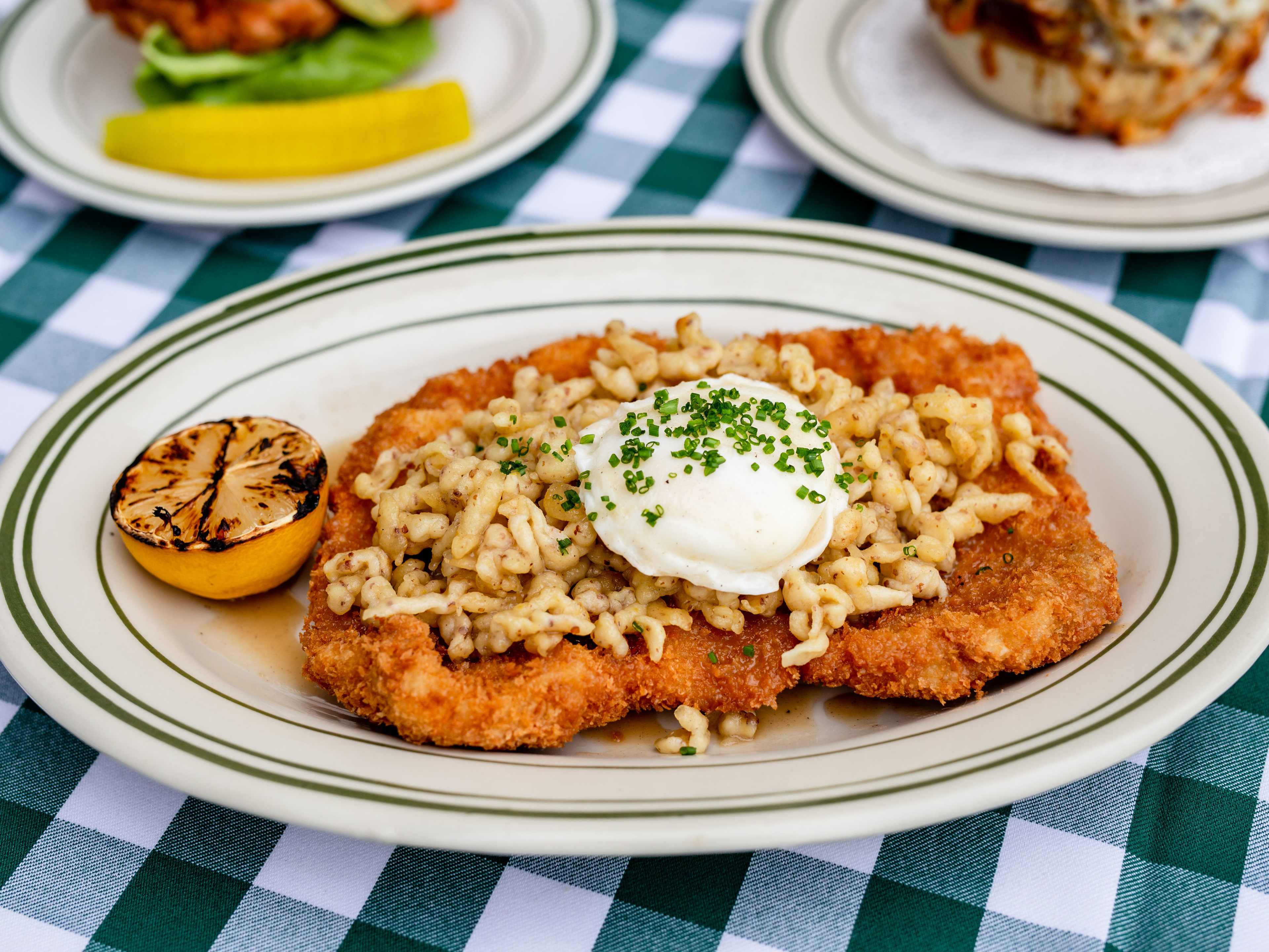 pork schnitzel with sour cream on an oval late on to pof a black gingham table cloth