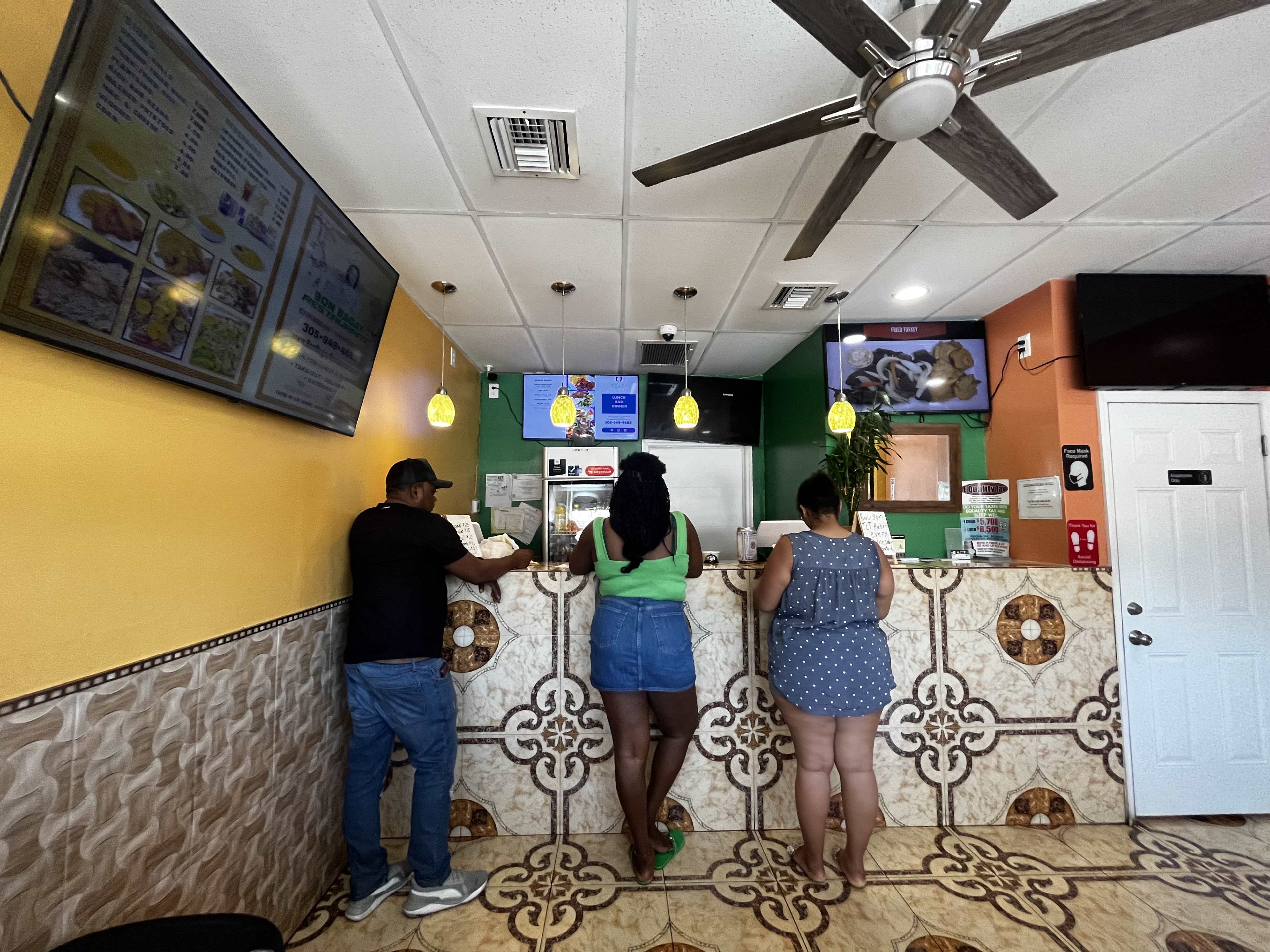 interior of a takeout restaurant with patterned tiles and a tv.