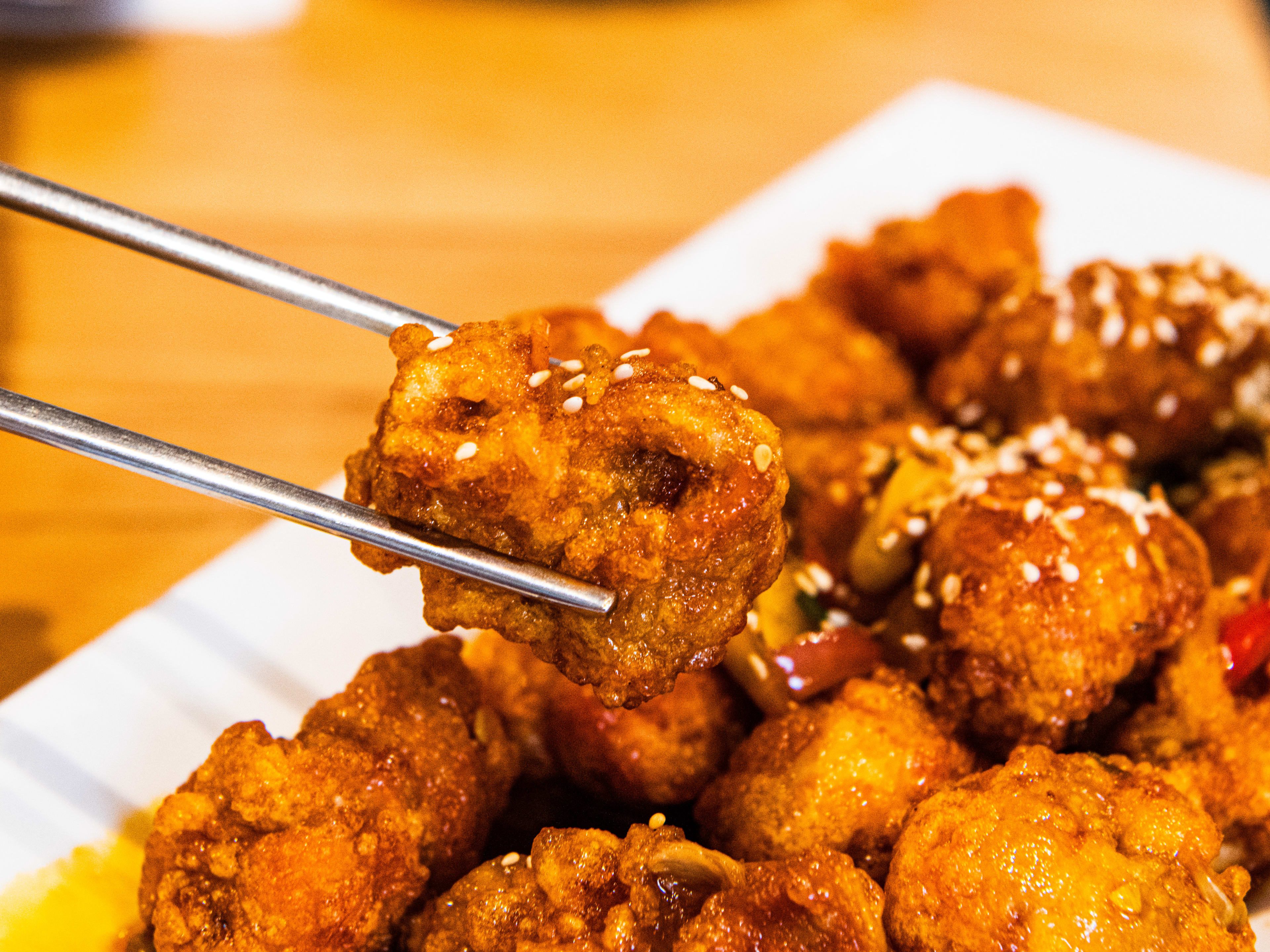 A person holds a piece of kan pung gi chicken with chopsticks from Imone.