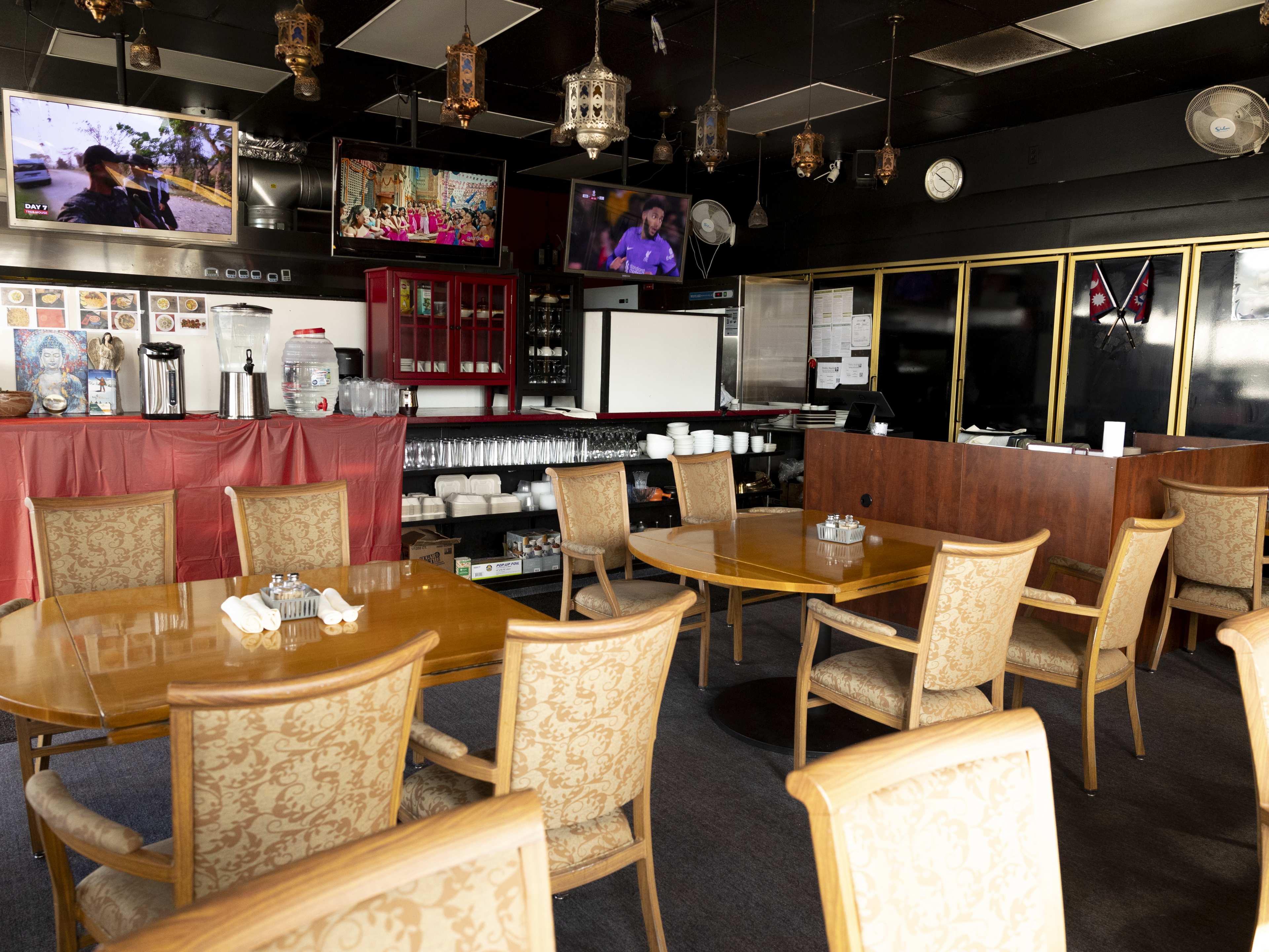 Dining room with wooden tables, black walls, and lanterns hanging from the ceiling