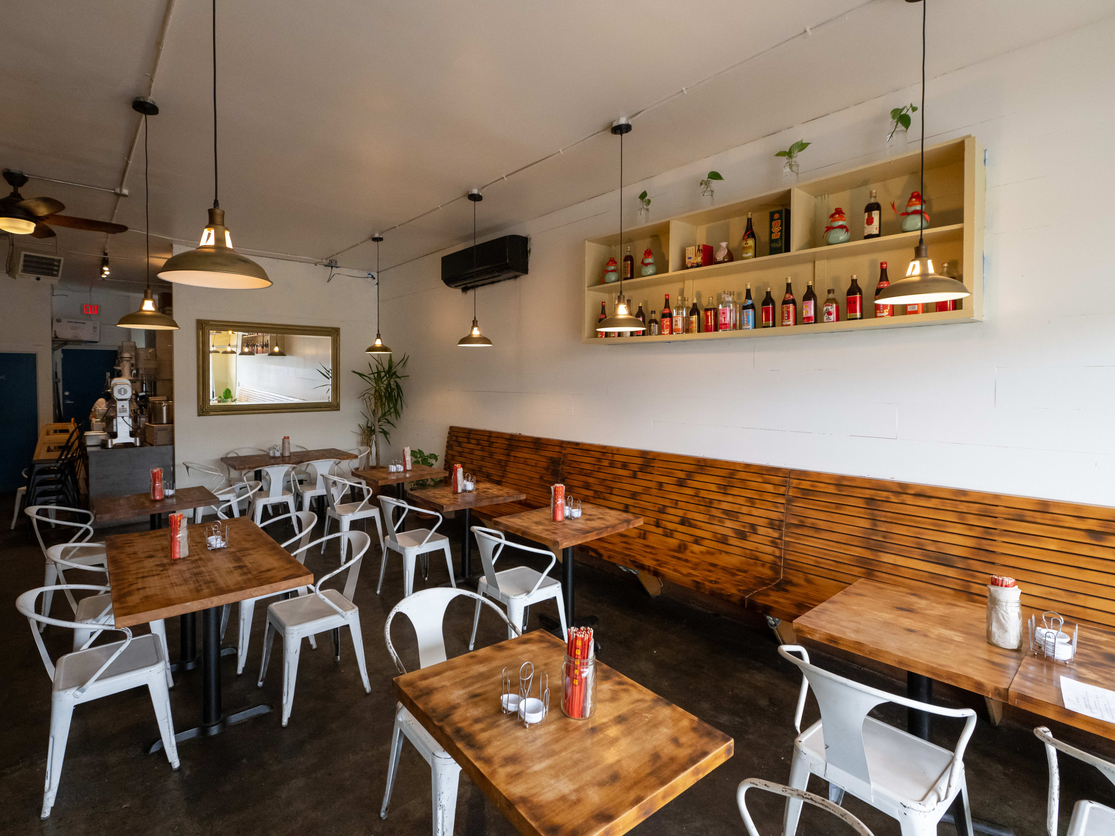 Dining room with wooden booths, white metal chairs, and chopstick holders on every table