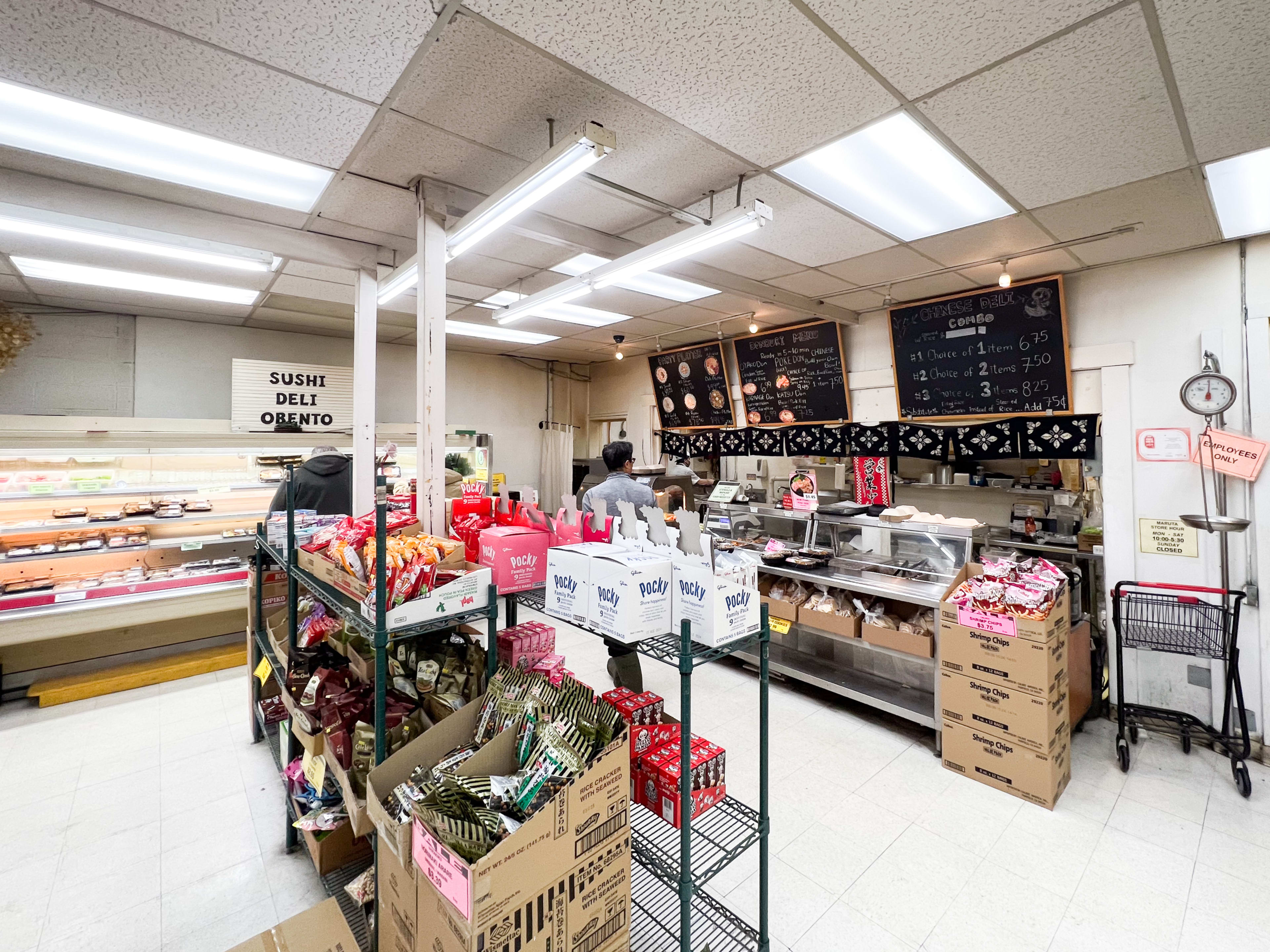 Japanese deli counter with shelves of sushi and sashimi.