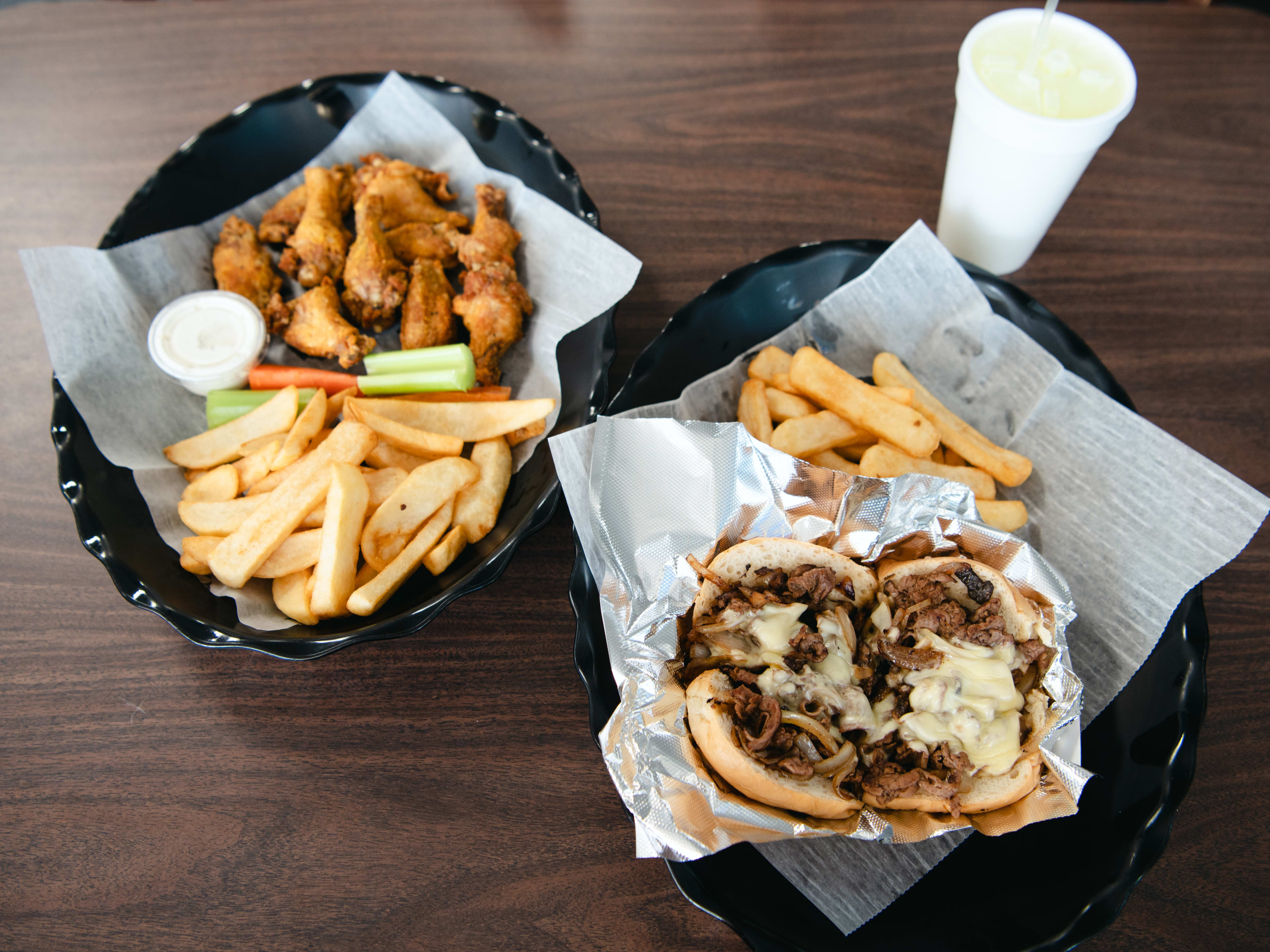 A table spread of wings, fries, and a cheesesteak.