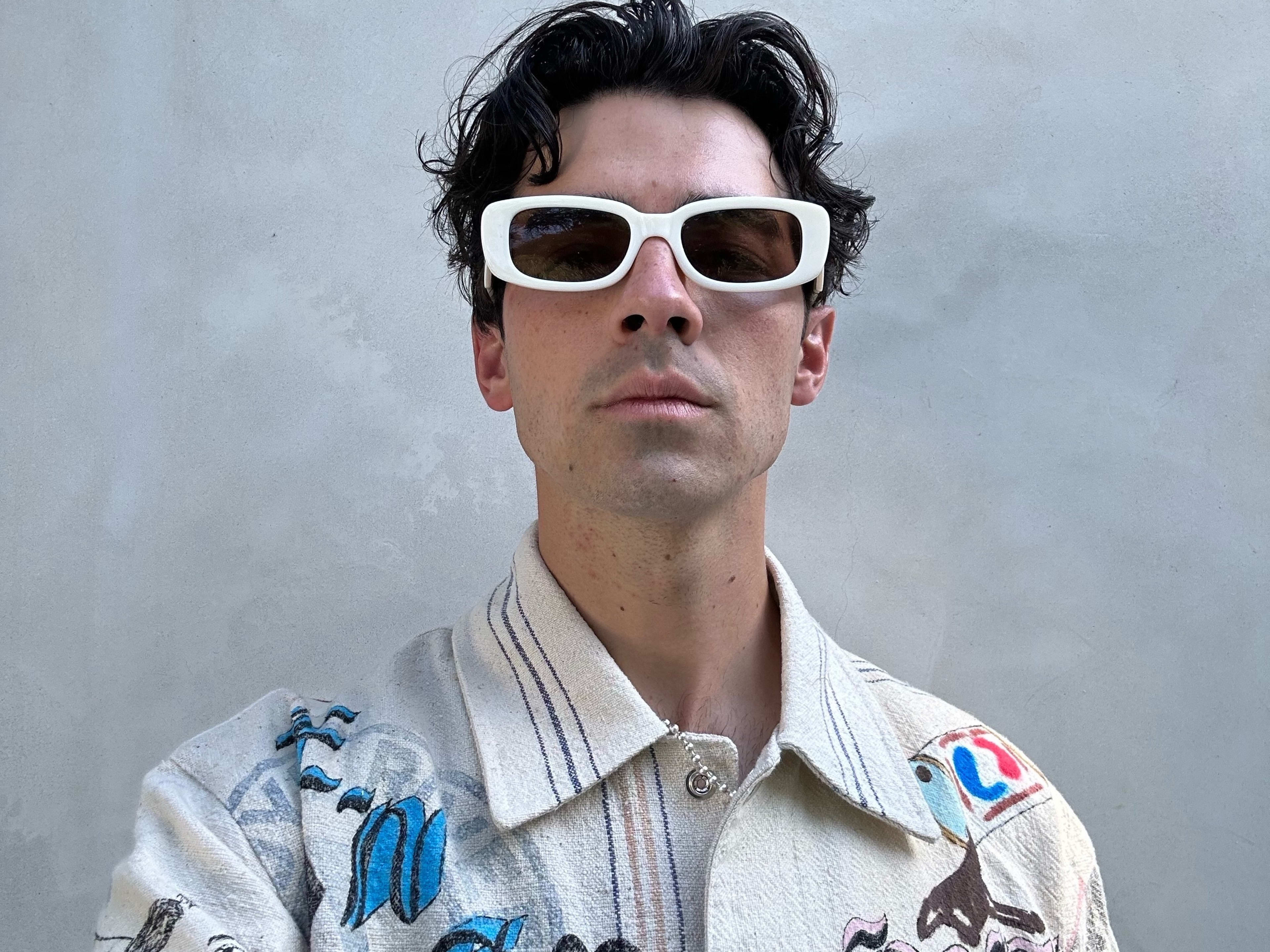 Joe Jonas wearing white sunglasses and a patterned shirt