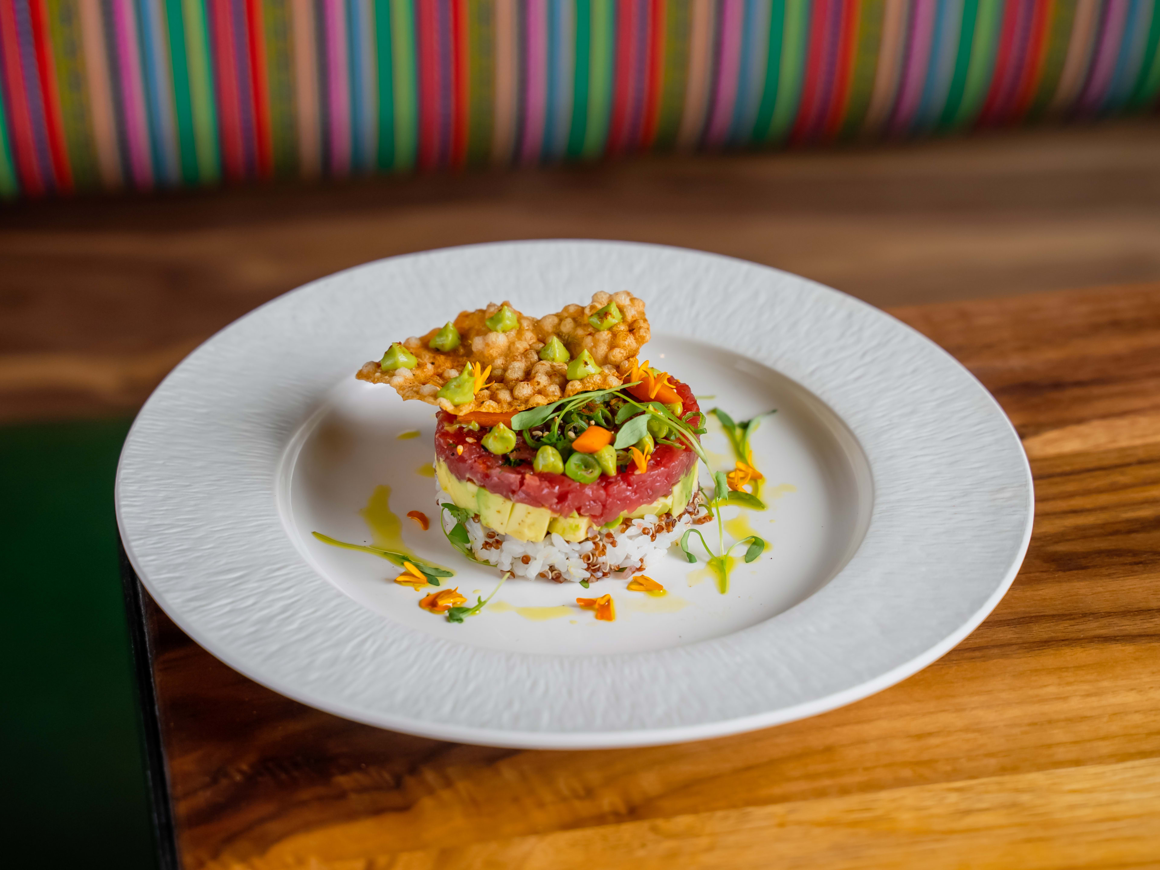 rice, avocado, and tuna stack with colorful garnish and a crisp topping