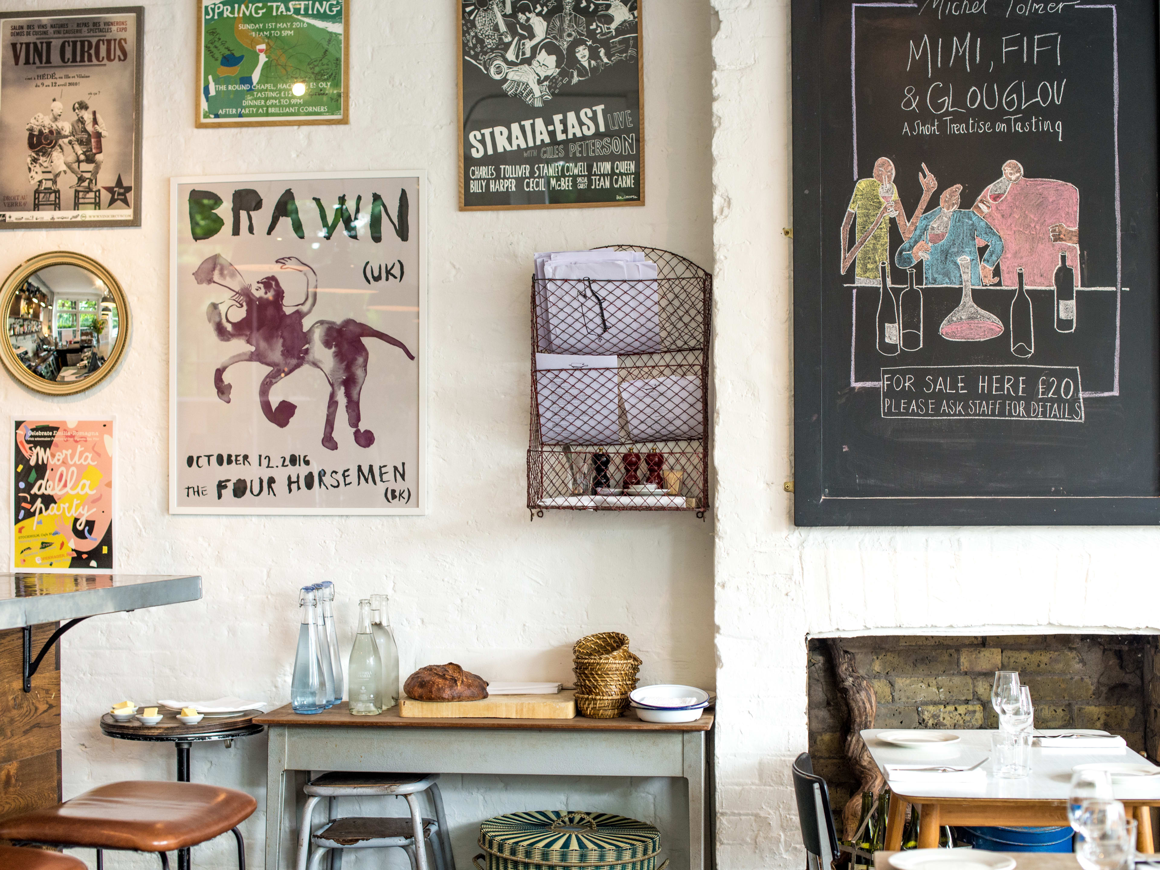 A photo of the wall at Brawn, featuring posters, an illustrated chalk board with winer drinks, and a bread station.