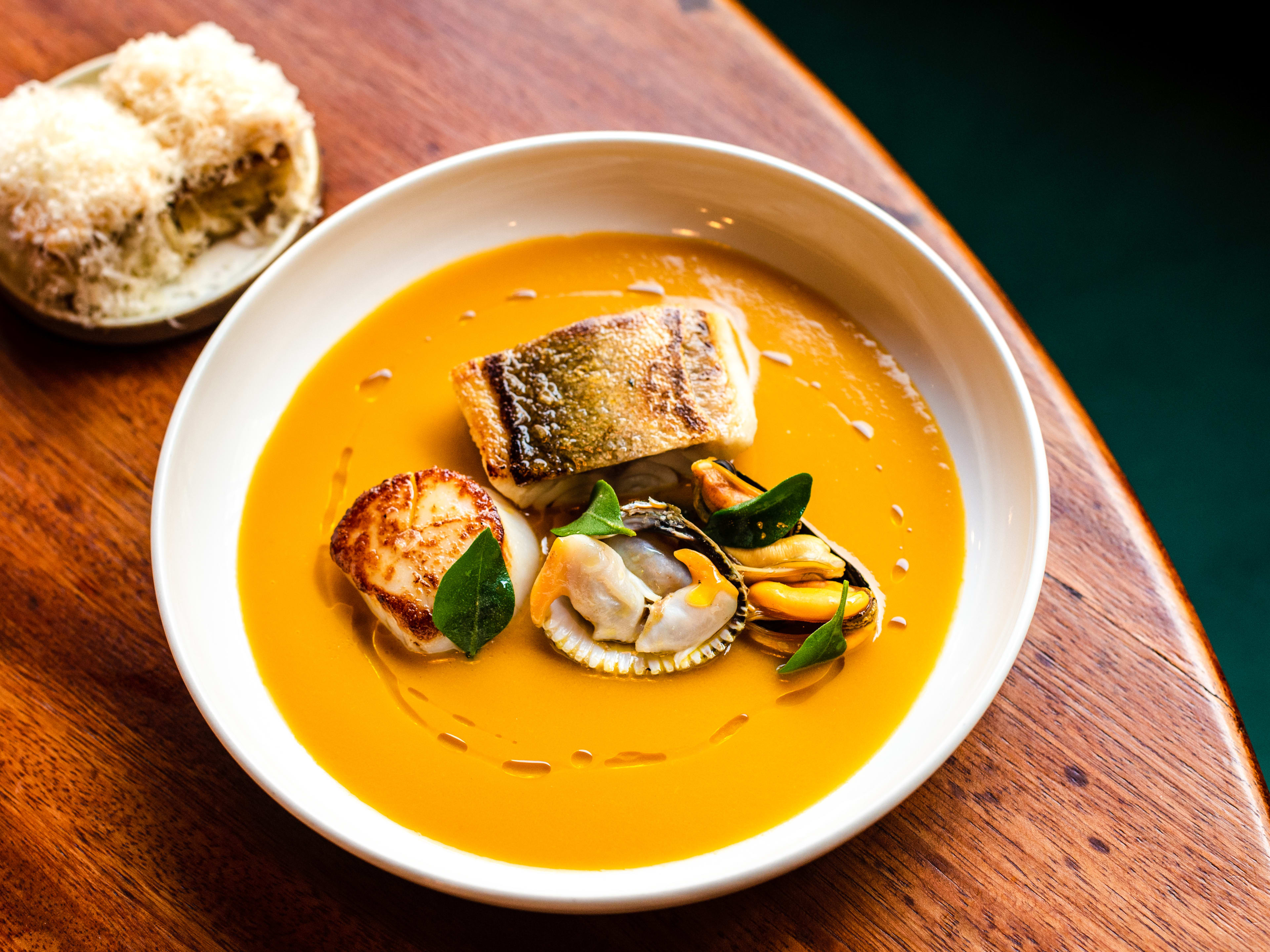 A bowl of fish stew with croutons on the side.