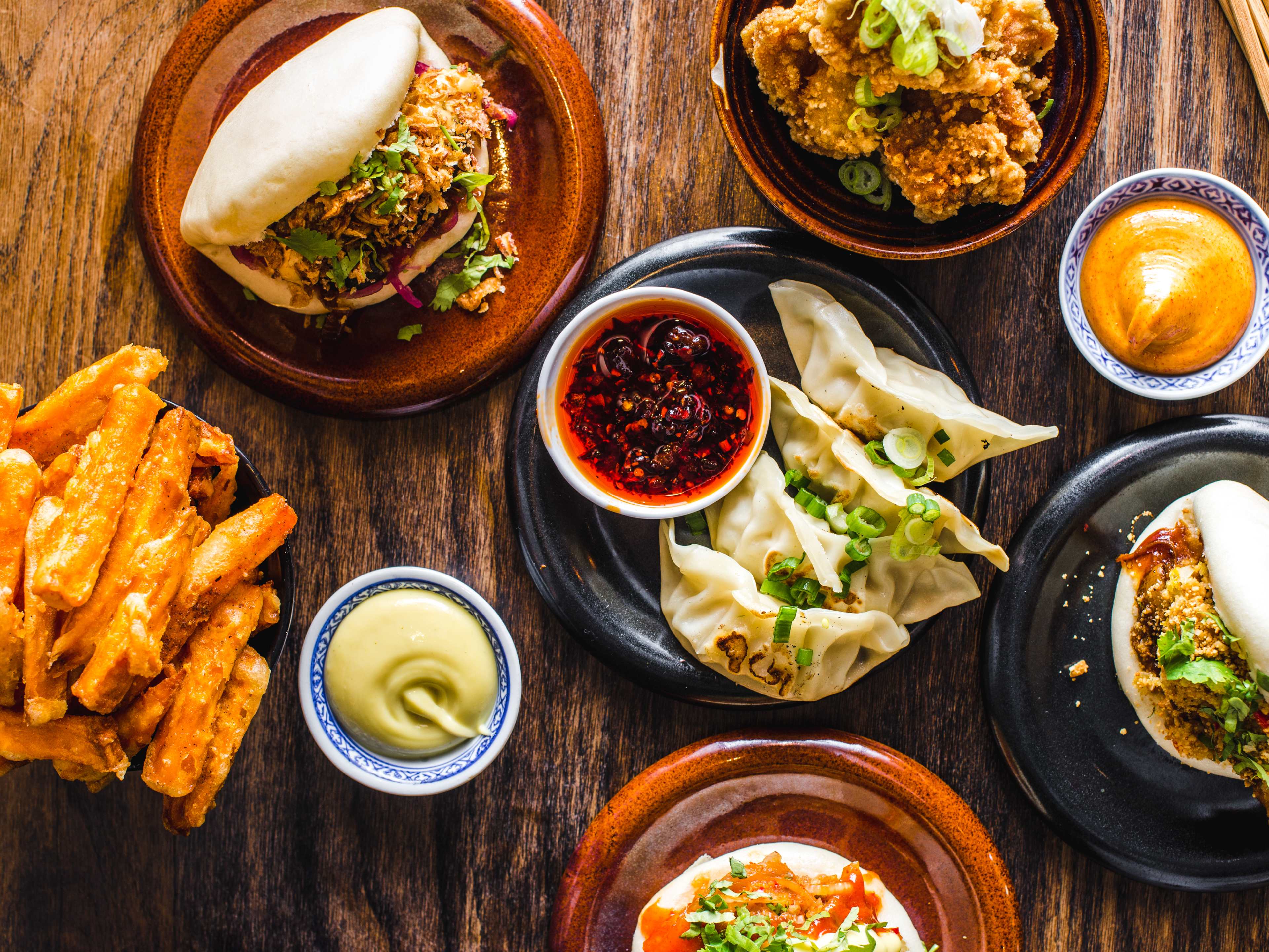 A spread of dishes from Mr Bao on a wooden table.