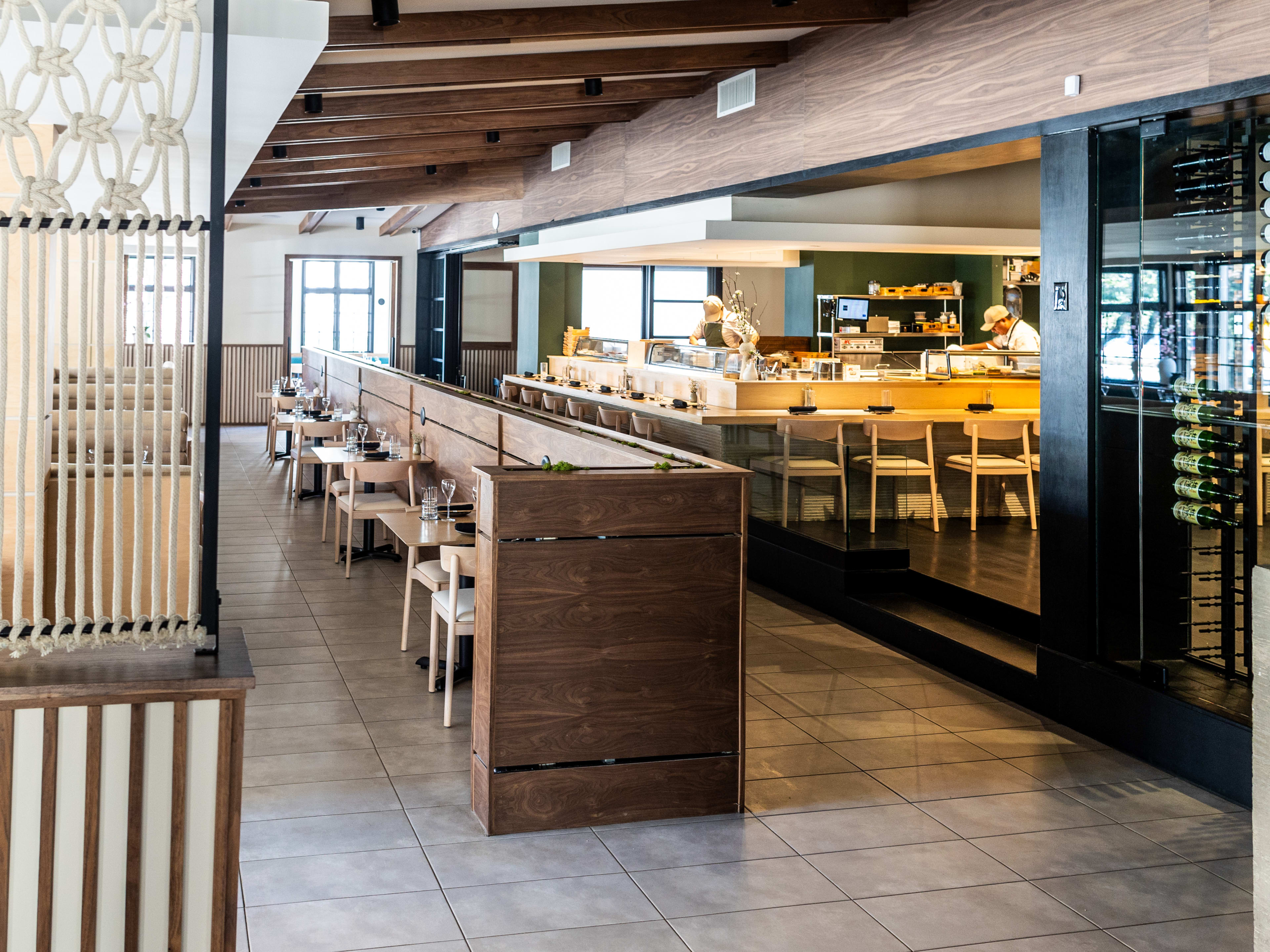 Japanese restaurant Katami interior with light wood, blue accents, and large windows.