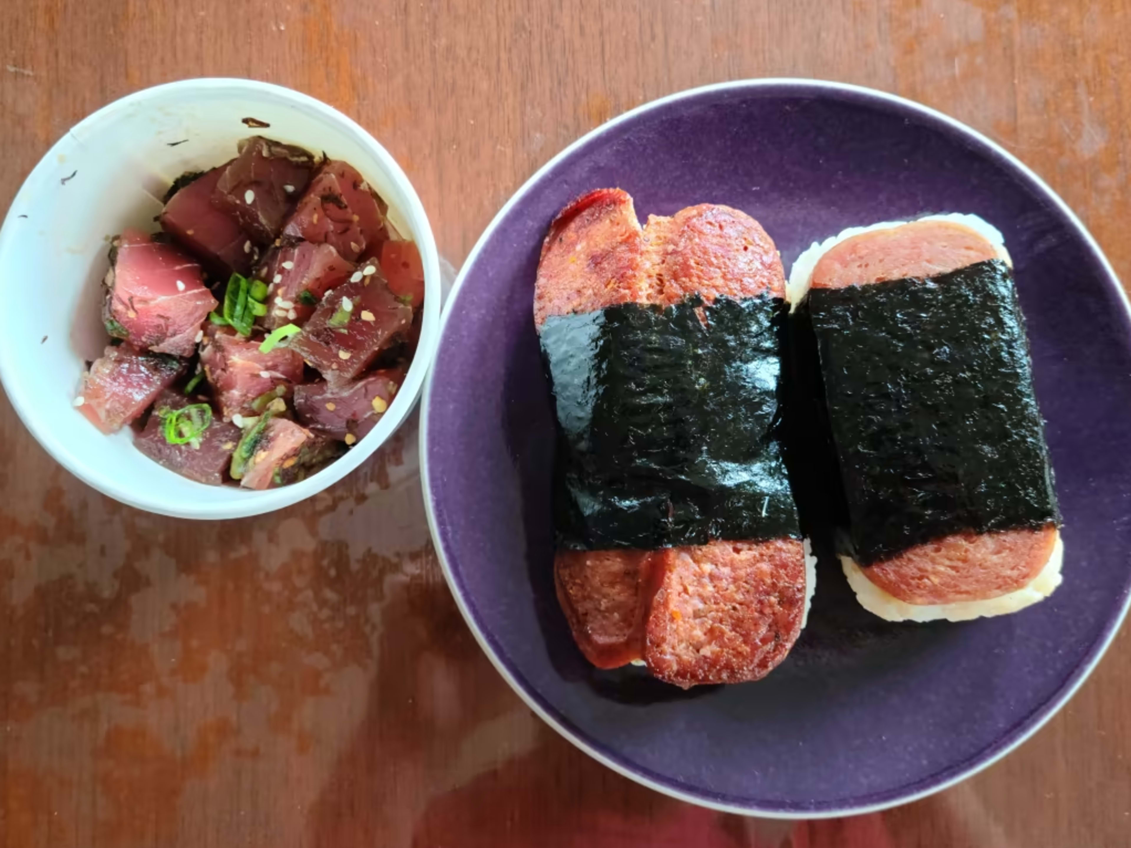 A bowl of poke next to a plate of spam musubi