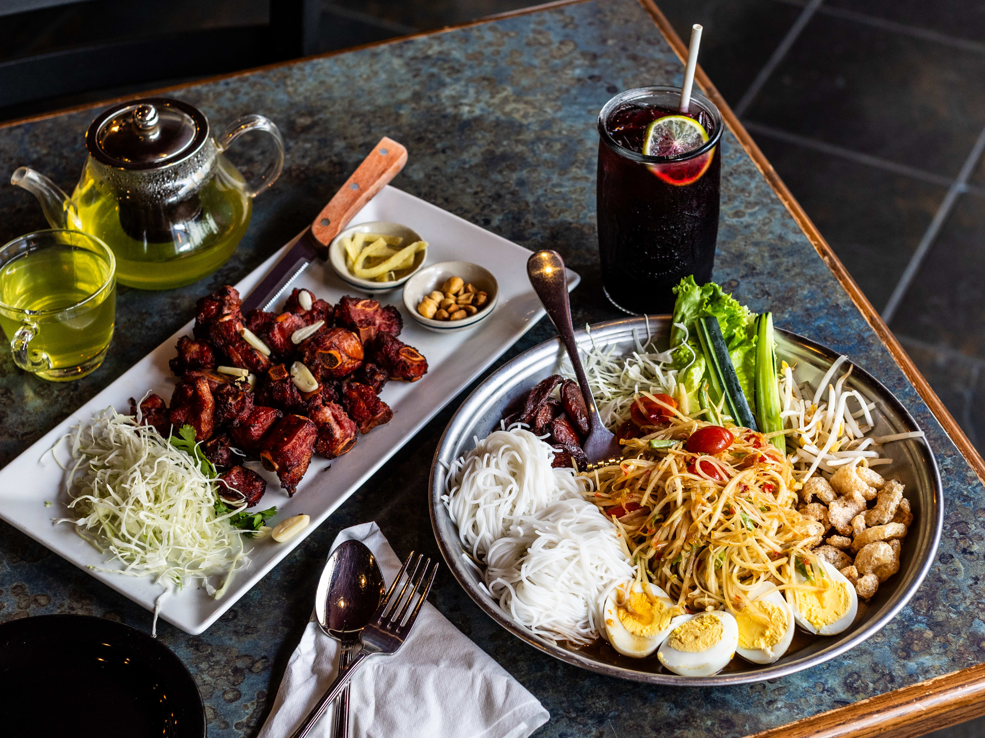 The tum tad, nam kradook, hibiscus tea and hot tea on a table at Khon Thai.