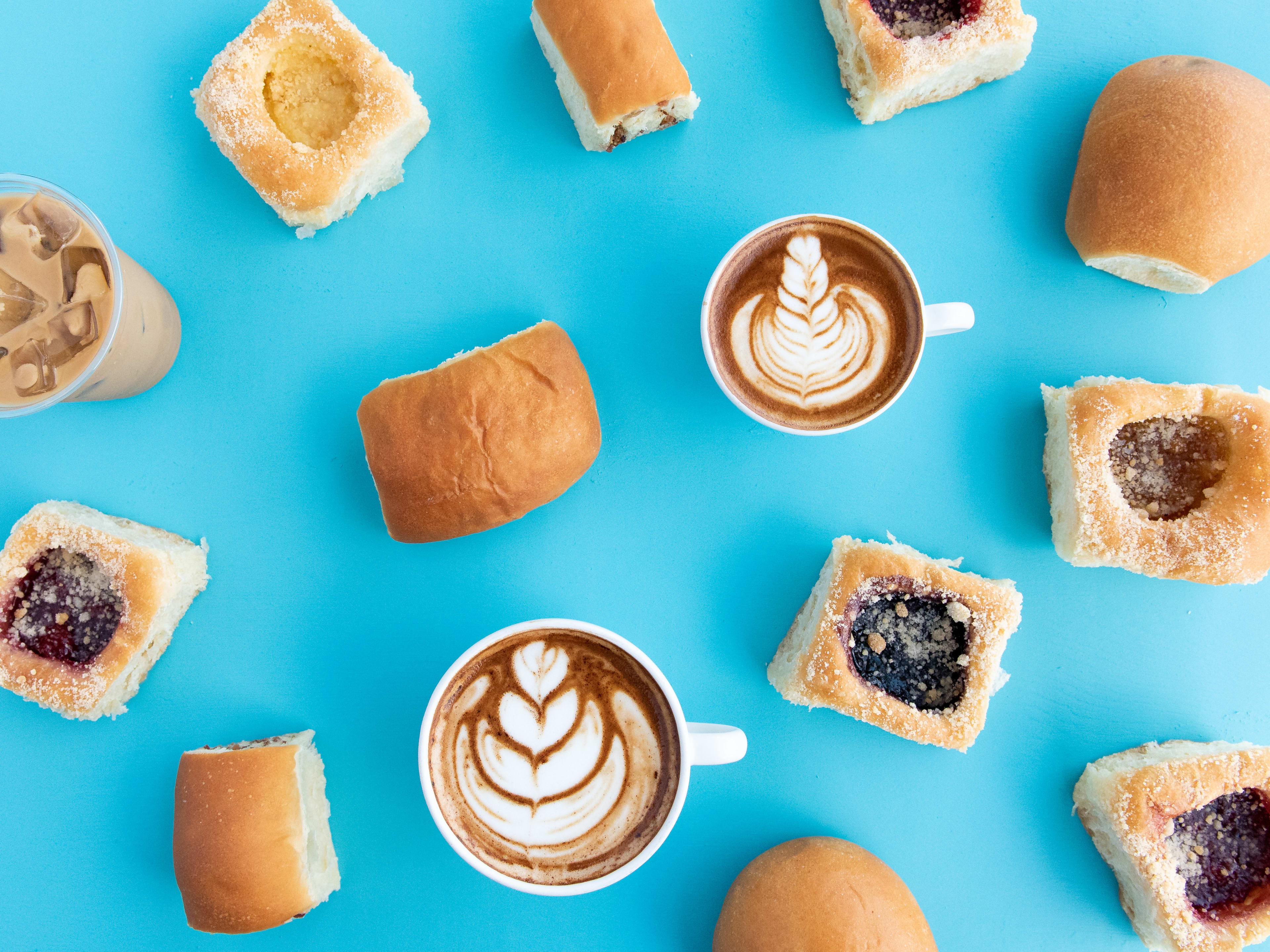 spread of multiple Kolache Shoppe kolaches with different coffee drinks