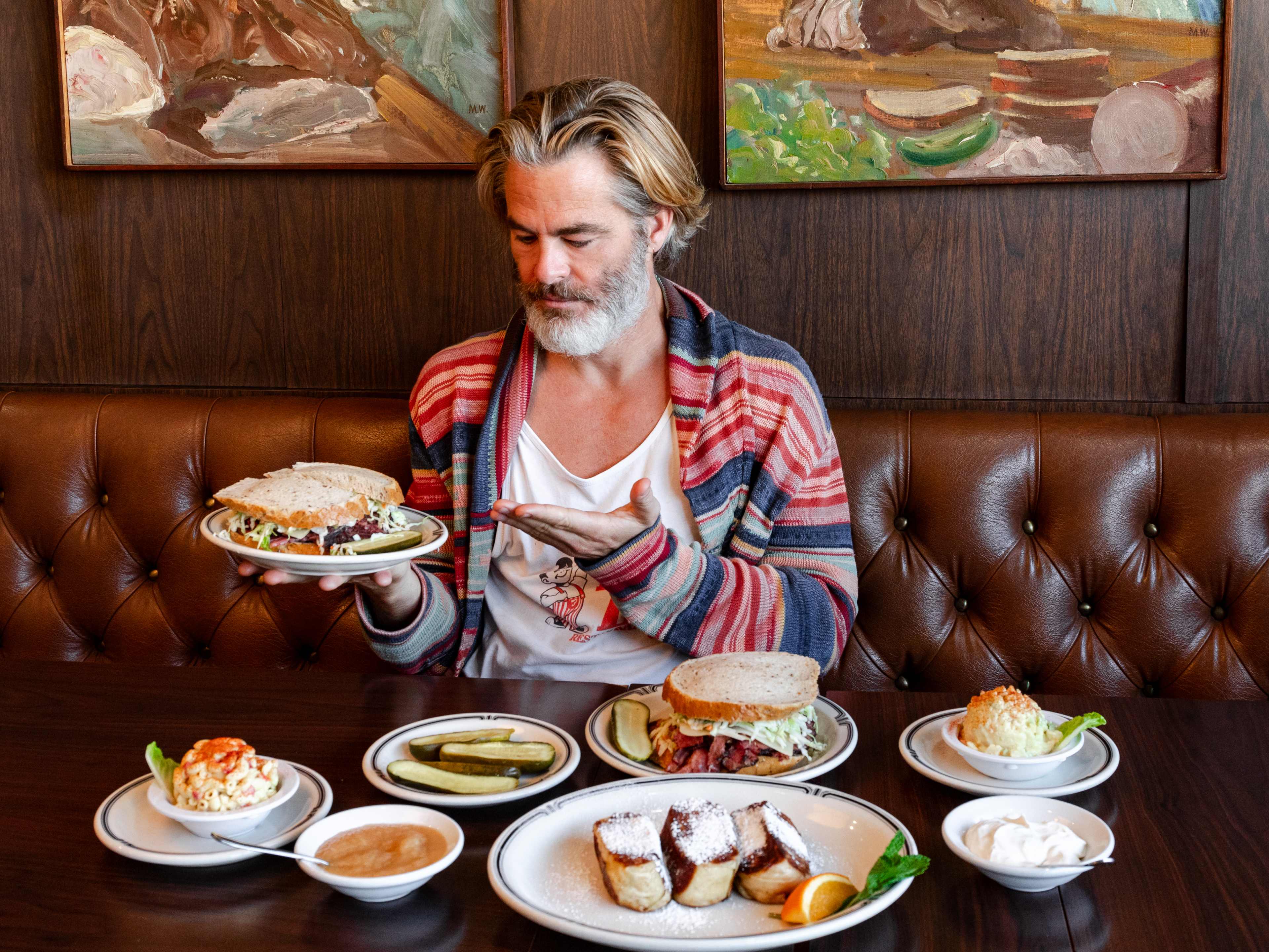 the actor chris pine holds up a sandwich on a plate