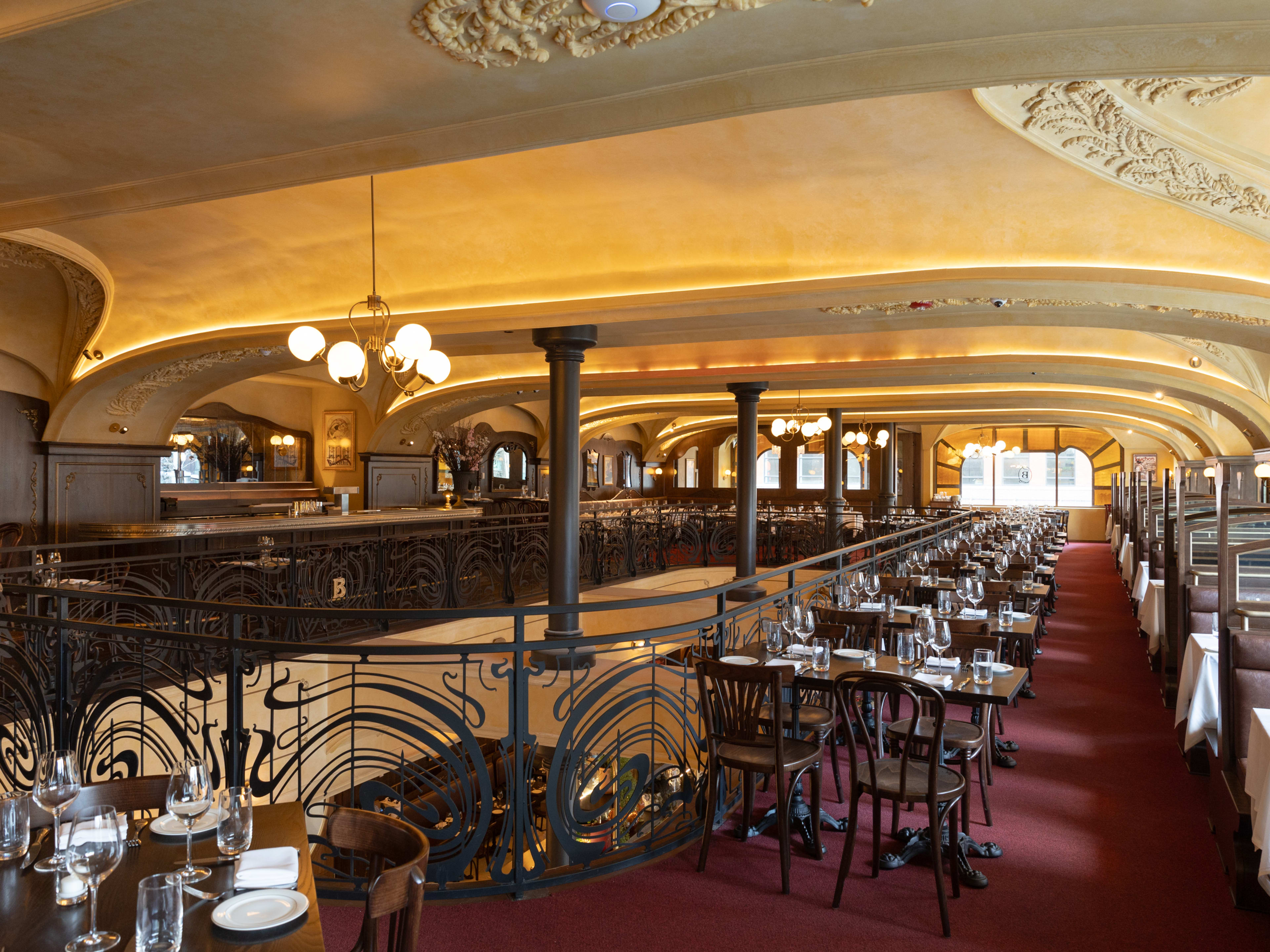 The second floor of a massive dinning room full of booths and tables next to a railing that looks into the first floor.