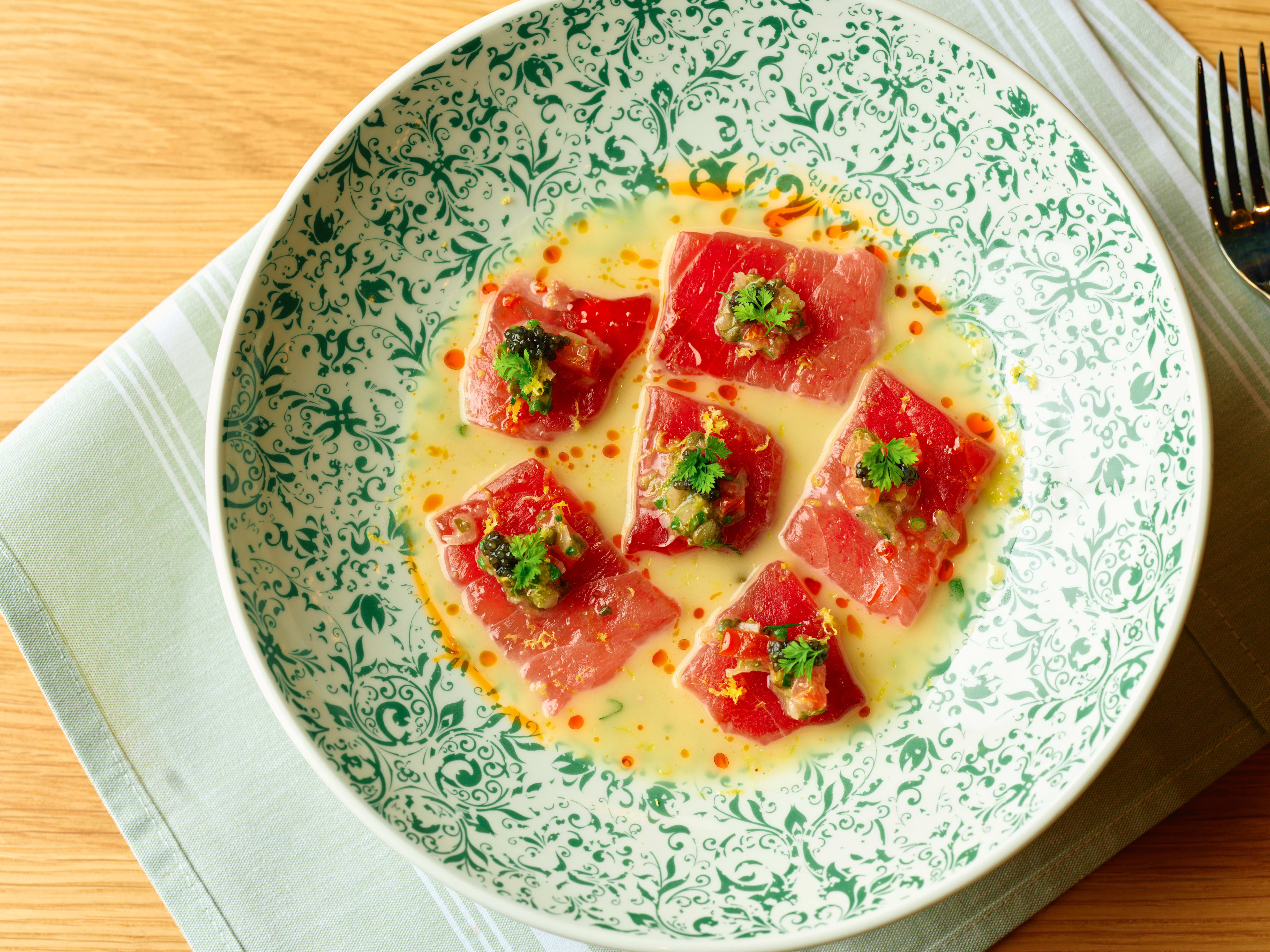 Tuna crudo topped with caviar in an ornately designed plate.