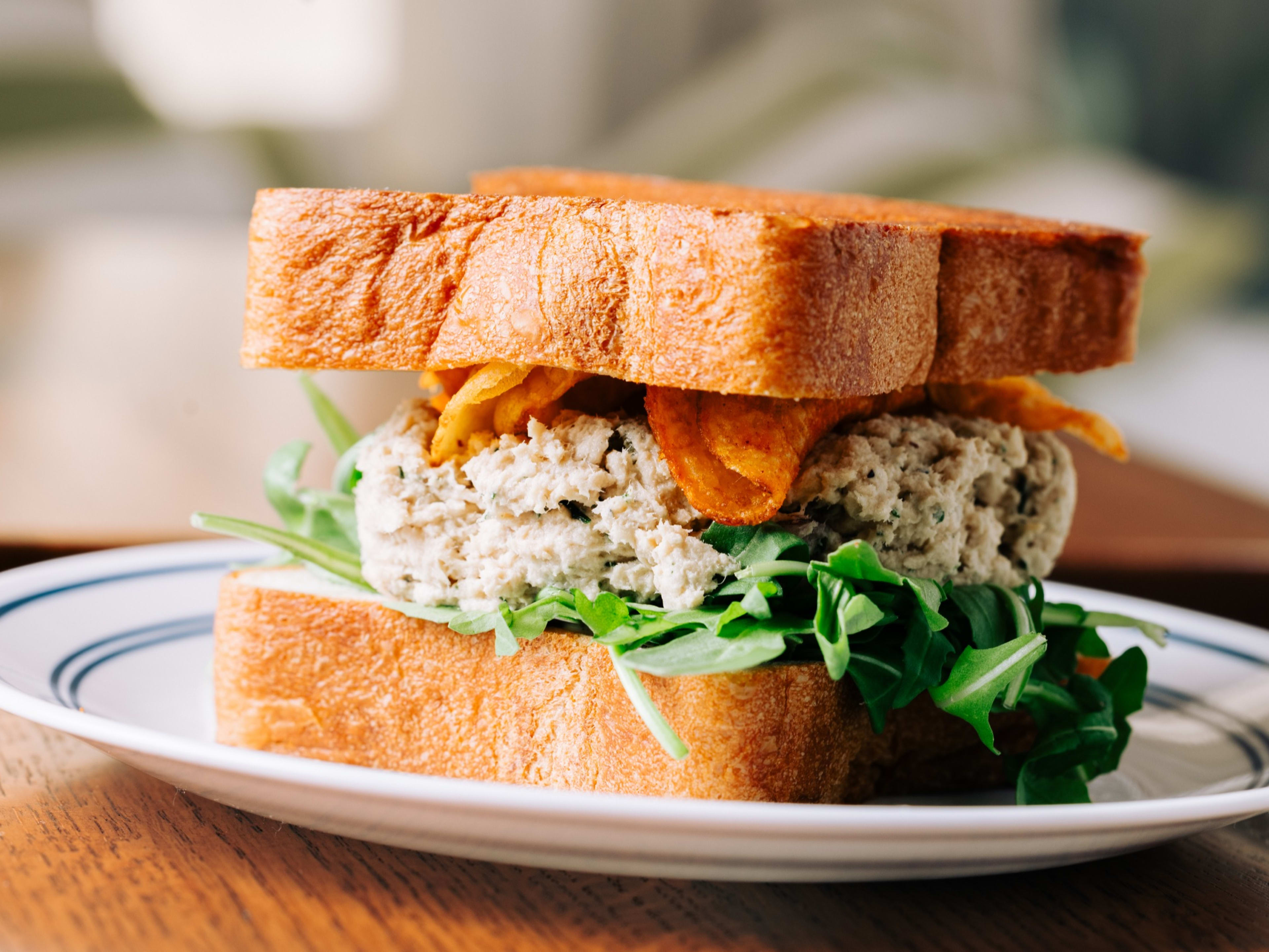 Tuna salad sandwich stuffed with arugula and chips.