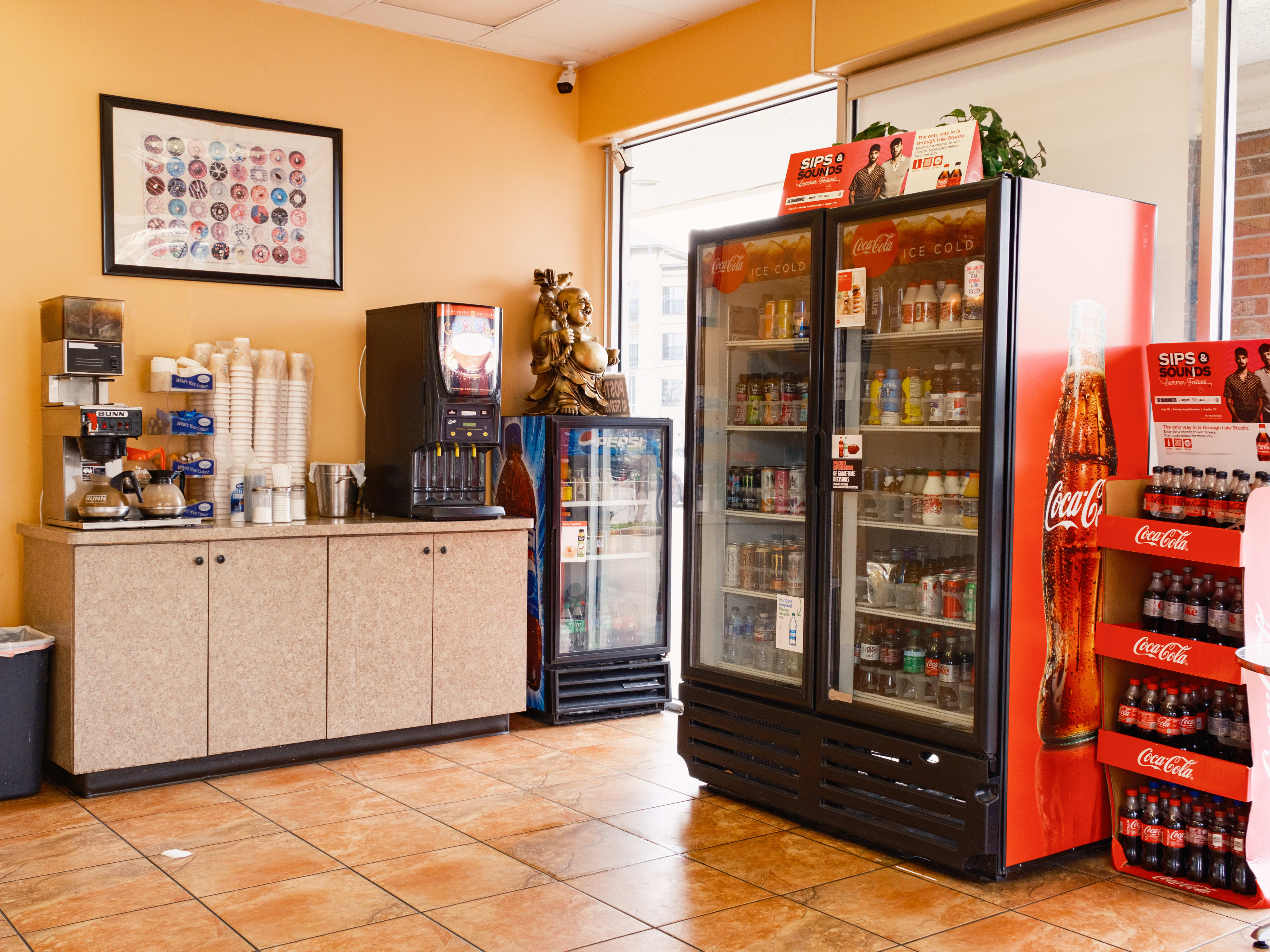 The interior of Le Donut with a coffee station and a large fridge with sodas.