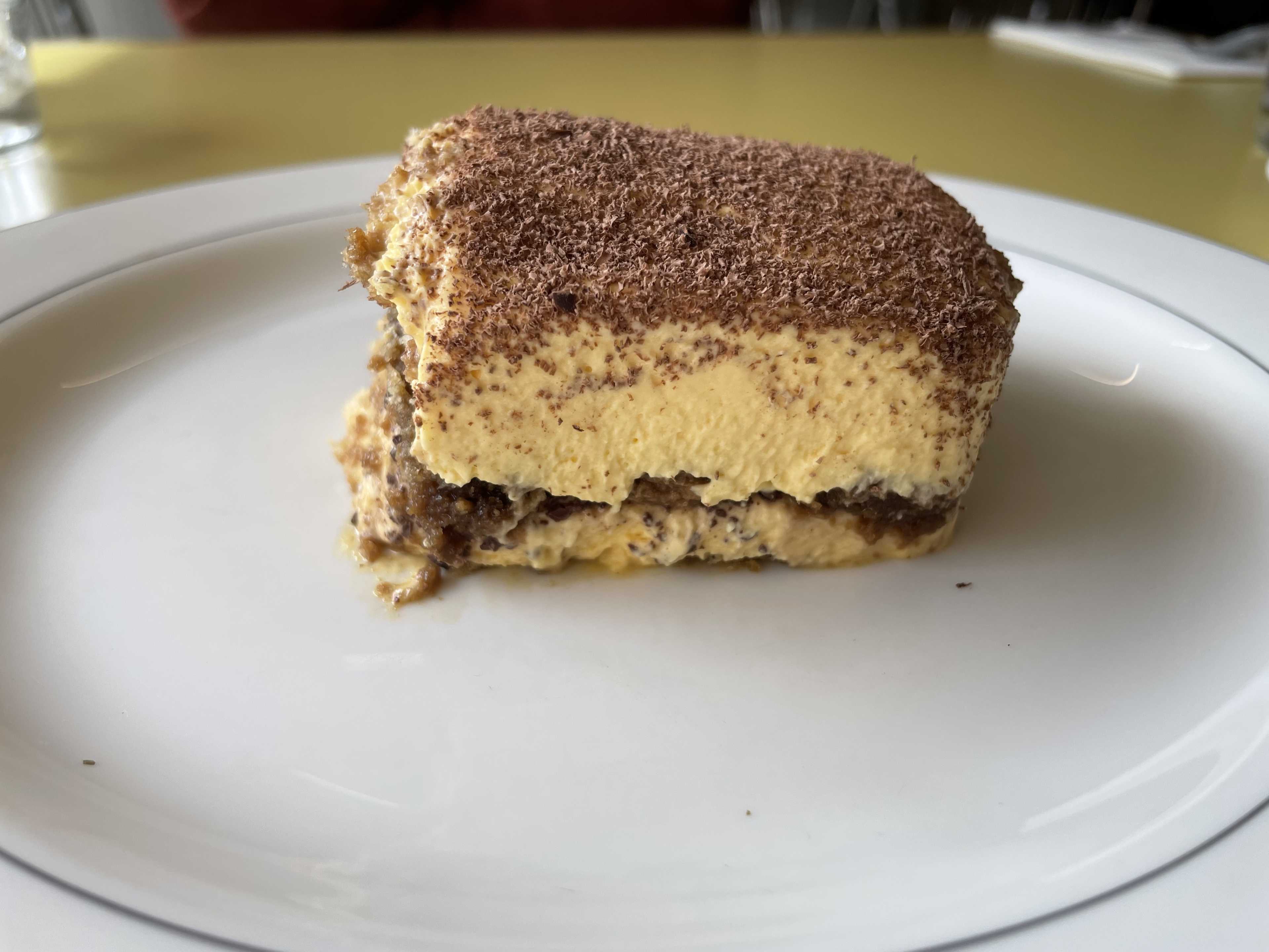 A slab of tiramisu on a white plate.