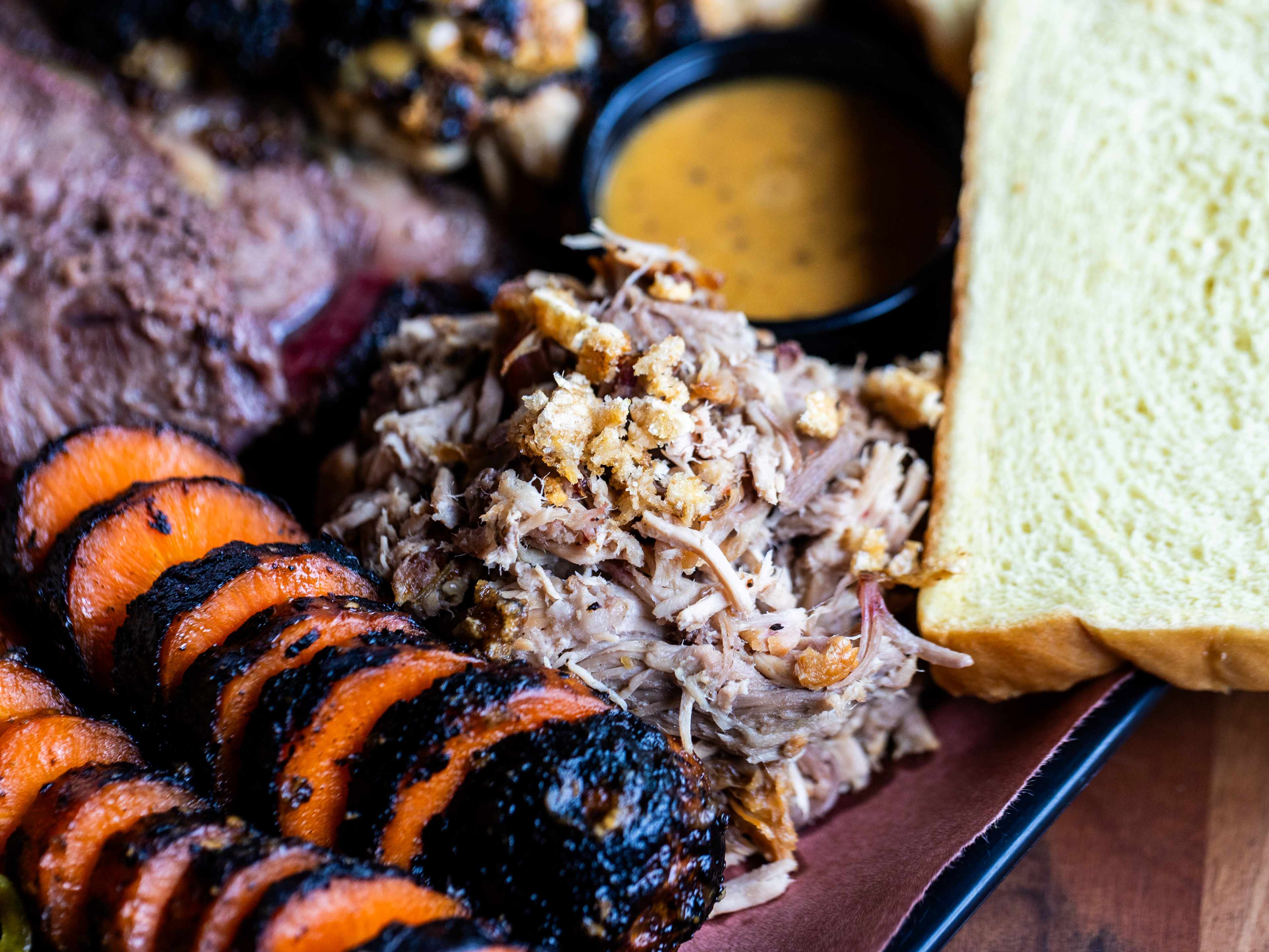 a platter of meat with smoked carrots and pulled pork