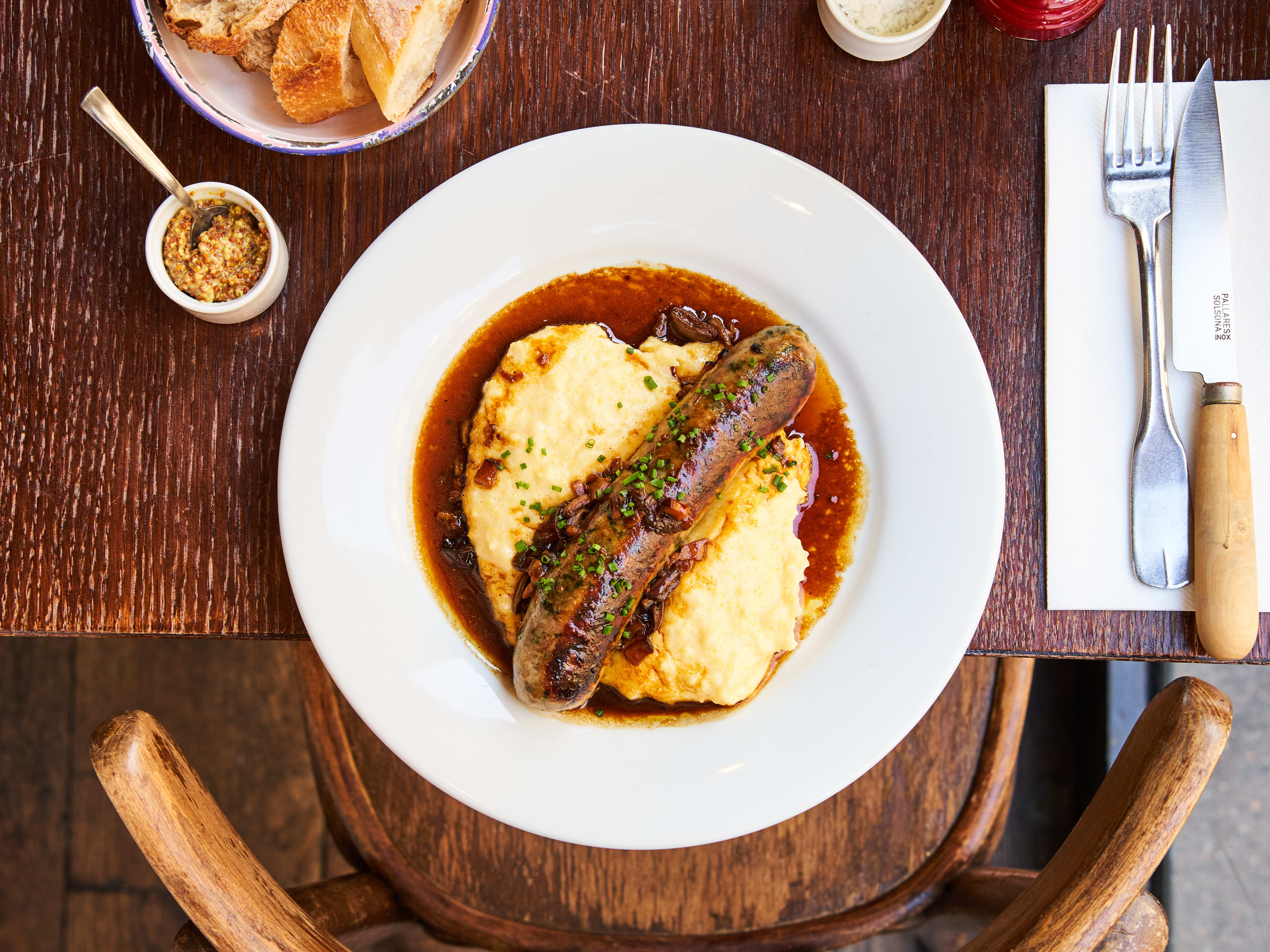 Polenta and sausage dish with a side of fresh bread at Les Arlots