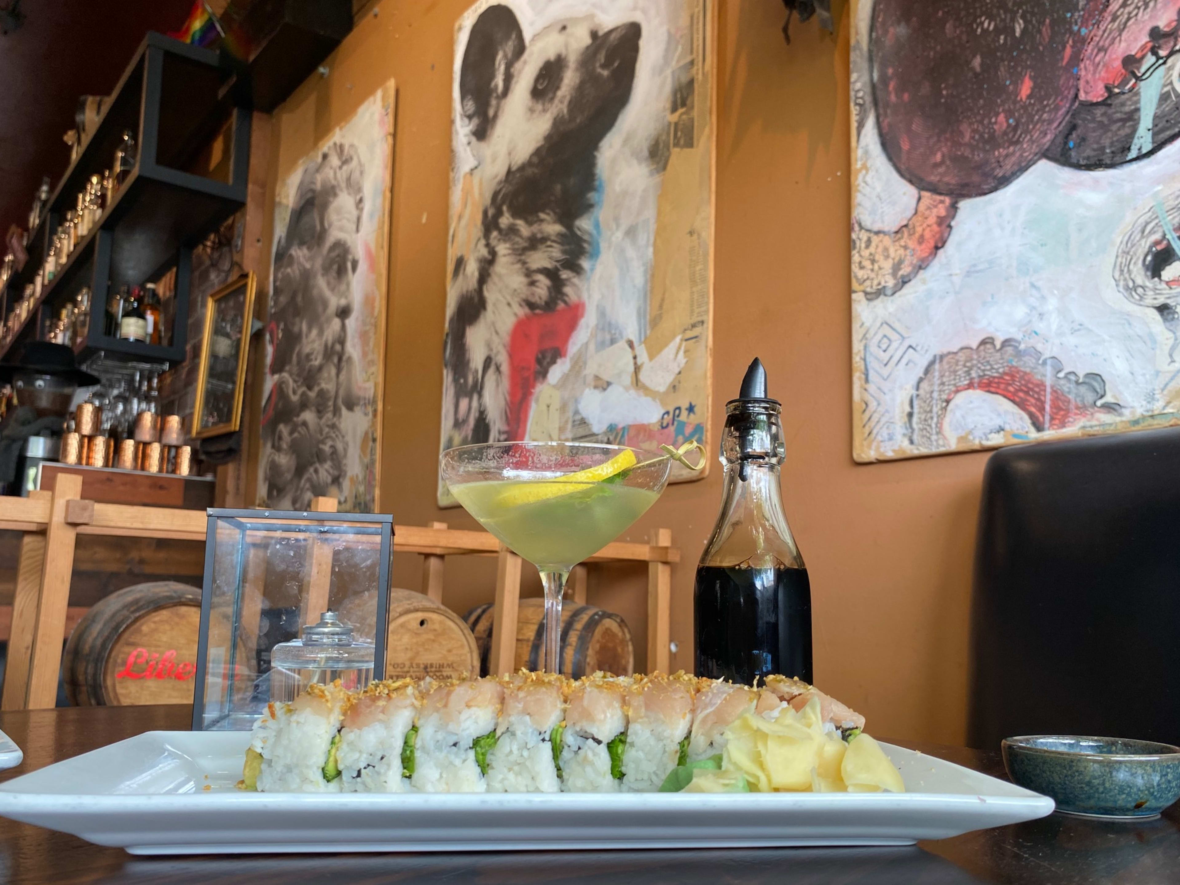 A sushi roll in the foreground with a painting of a german shepherd in the background at a Seattle bar