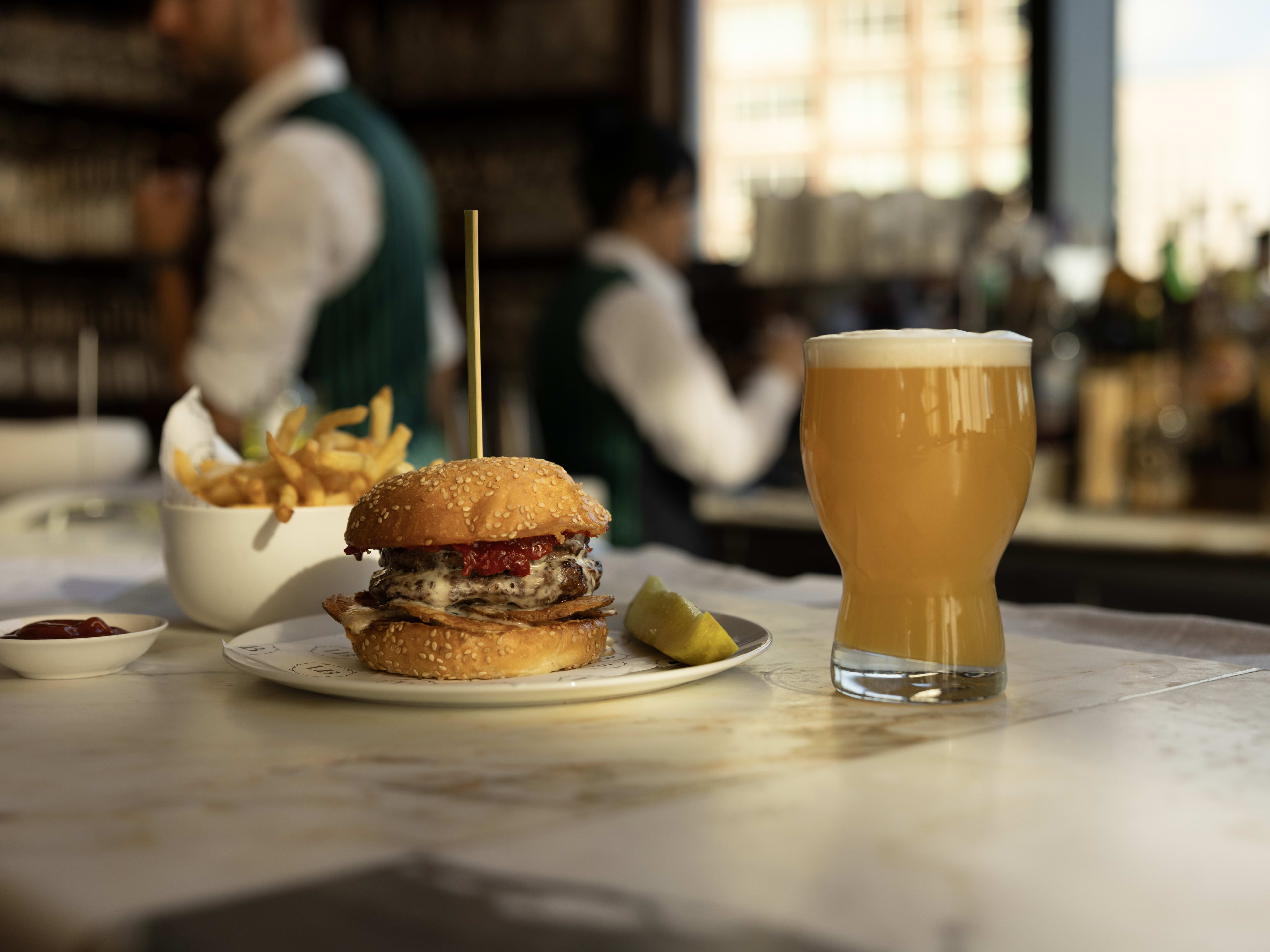 Burger with a side of fries and a draught beer at Long Bar & Terrace