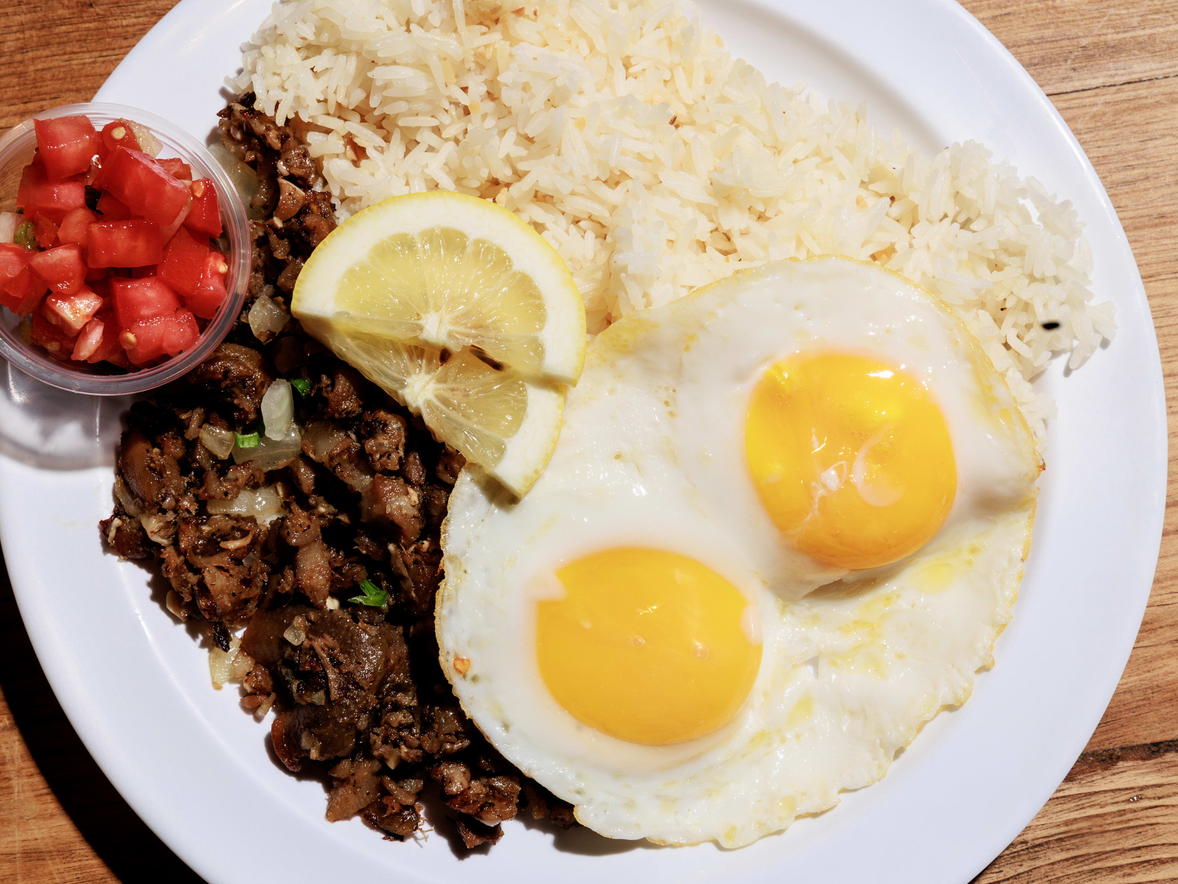 plate with sunny-side-up eggs, pork sisig, and garlic rice