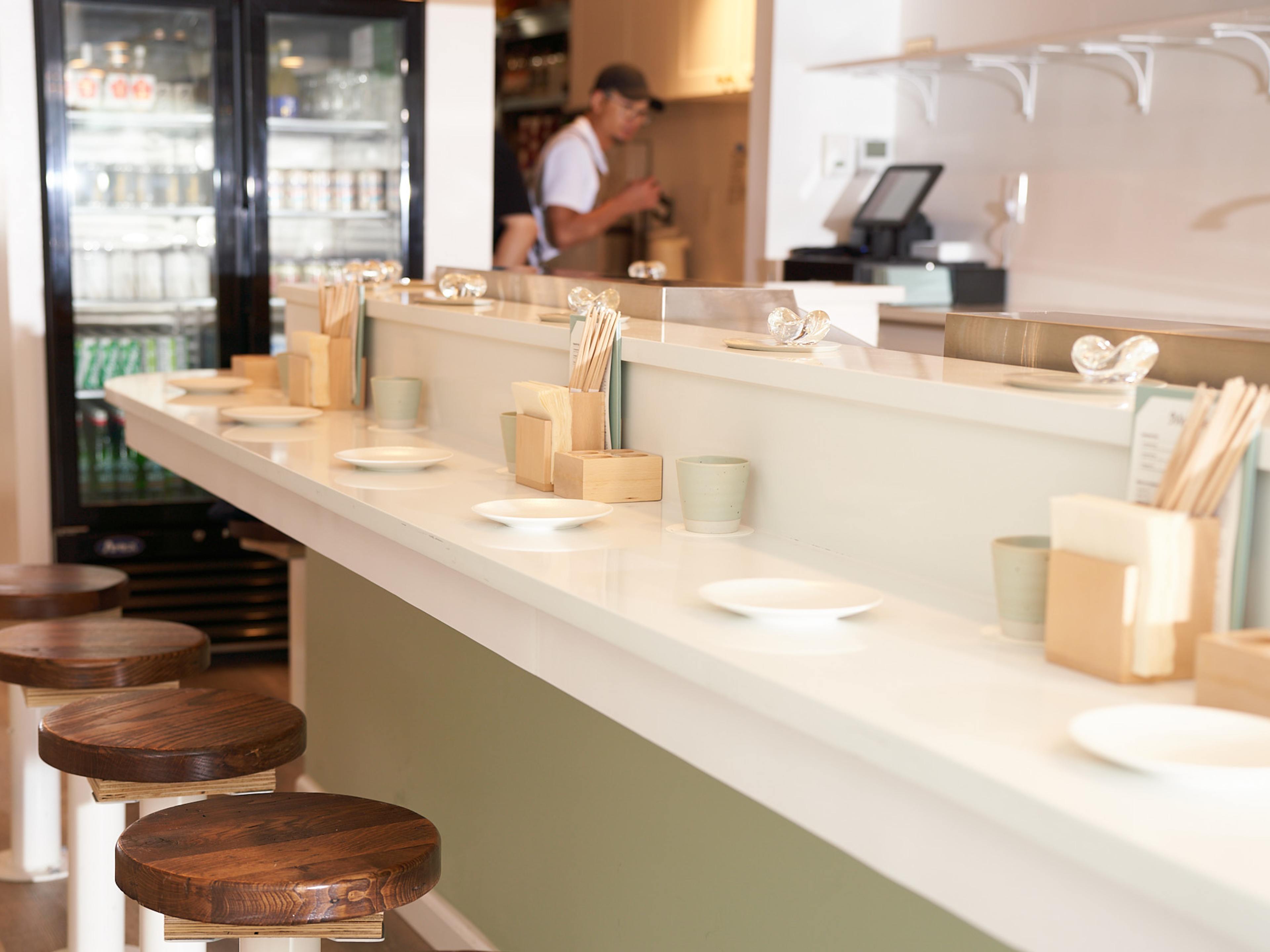 A restaurant counter with a few stools in front of it.