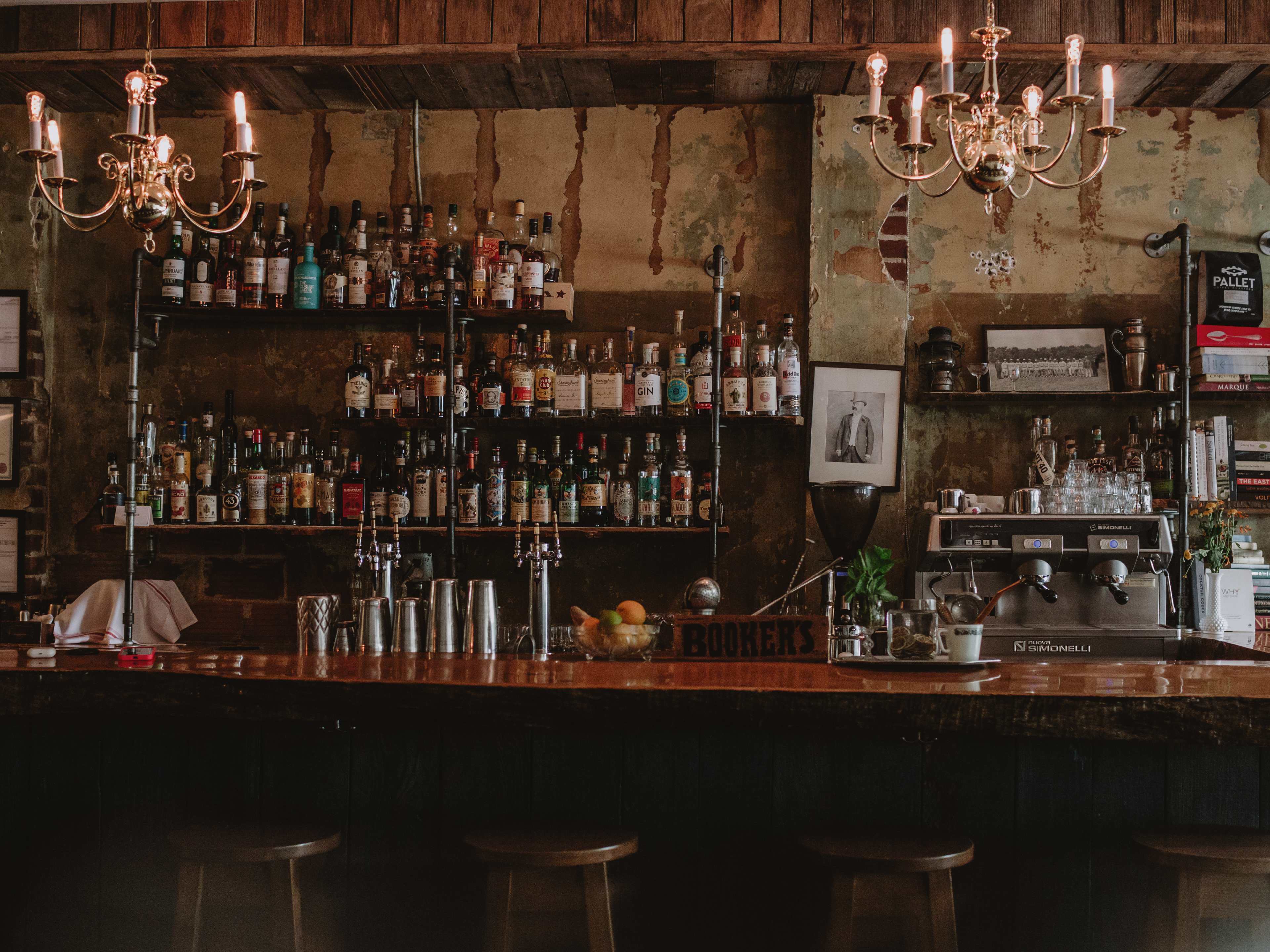 An old-looking bar with dramatic candlestick chandeliers band a worn wall inside The Mackenzie Room in Vancouver