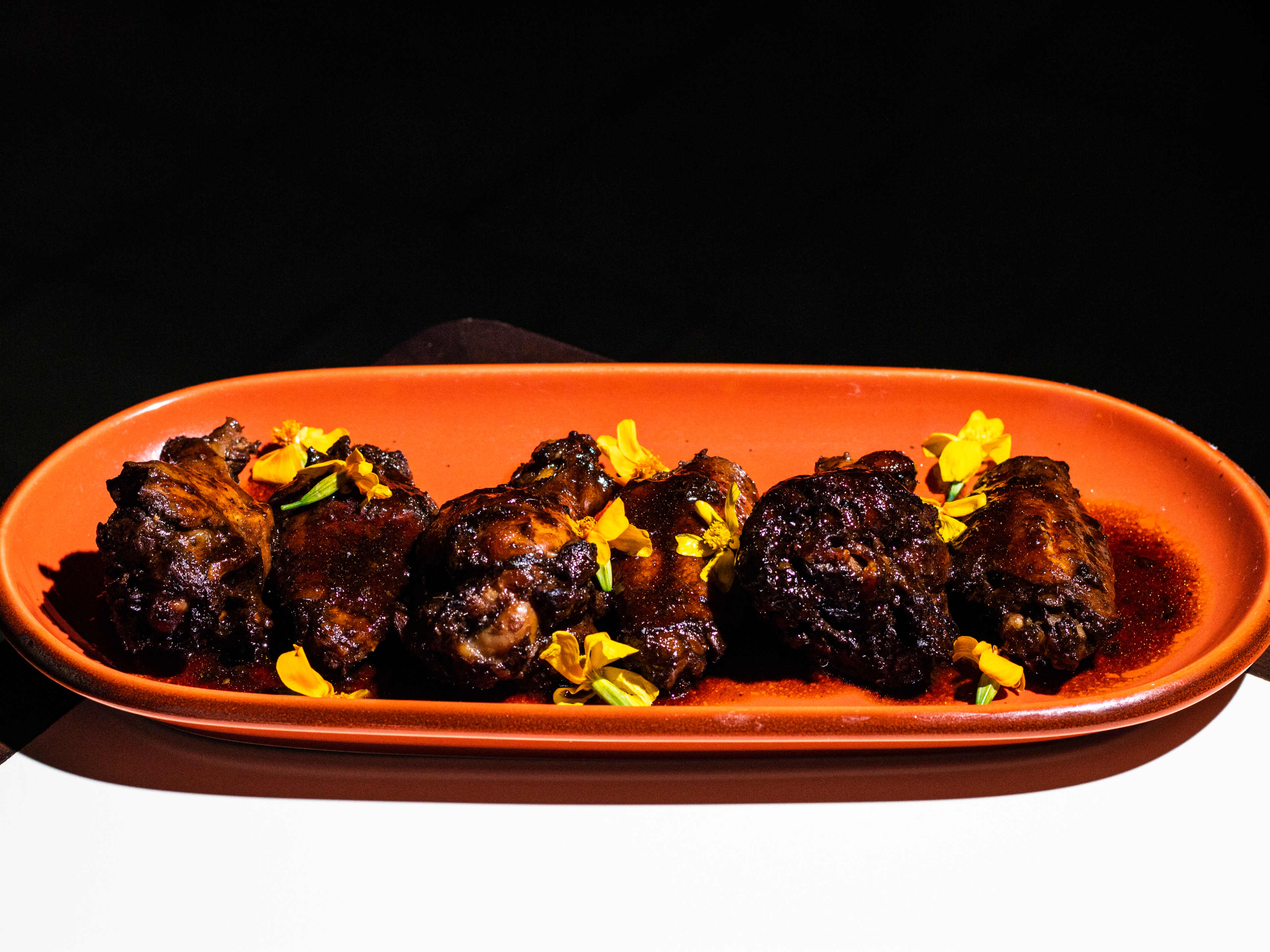 Wet jerk wings garnished with yellow flowers.